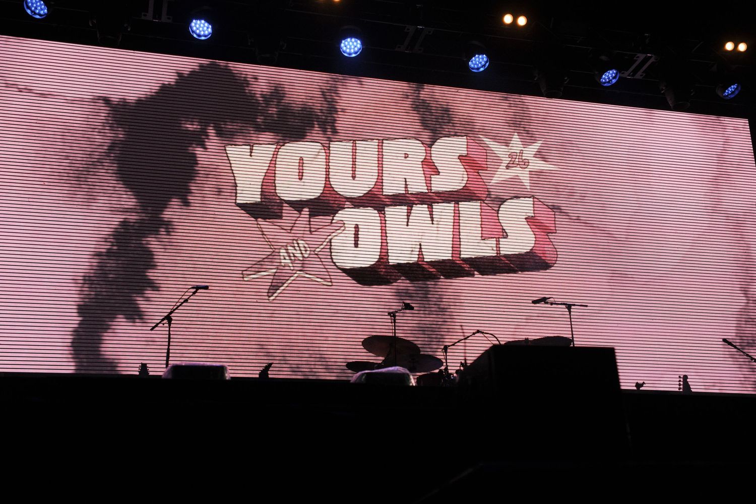 Concert stage with large screen displaying Yours Owls band logo with star graphics and dramatic smoke effects.
