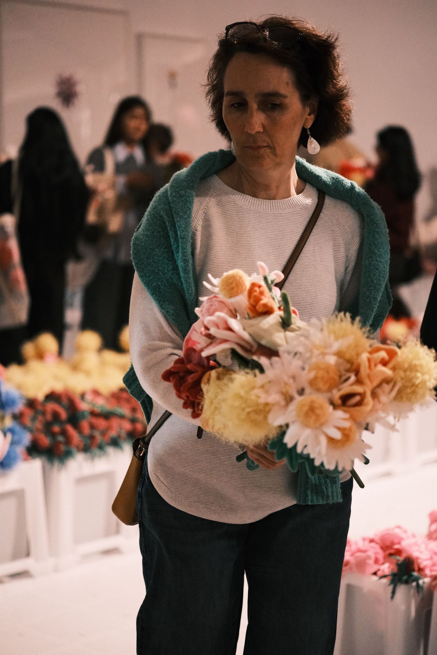Woman holding colorful bouquet of artificial flowers at an indoor flower exhibition.