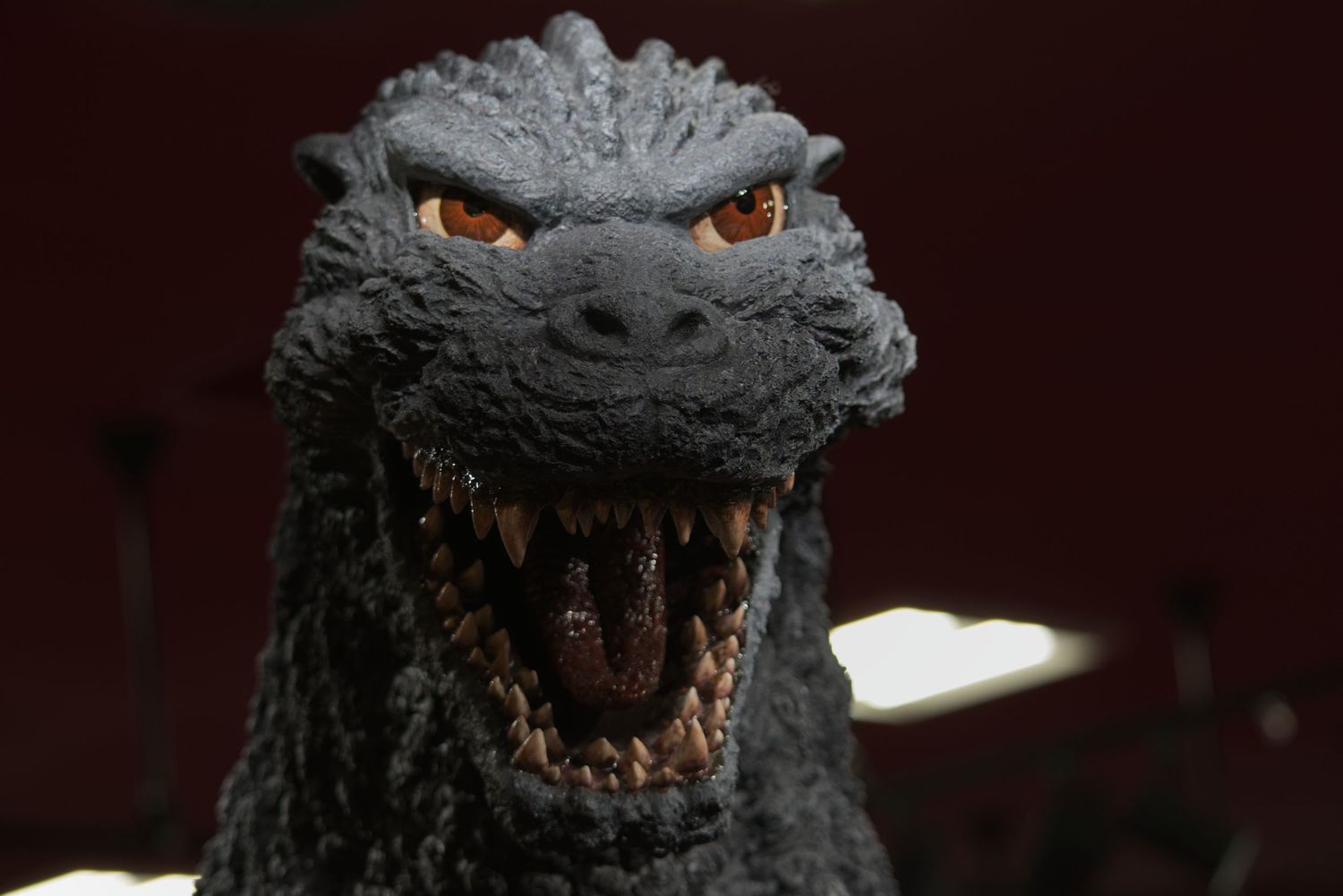Close-up of a detailed Godzilla figure with open mouth and orange eyes.