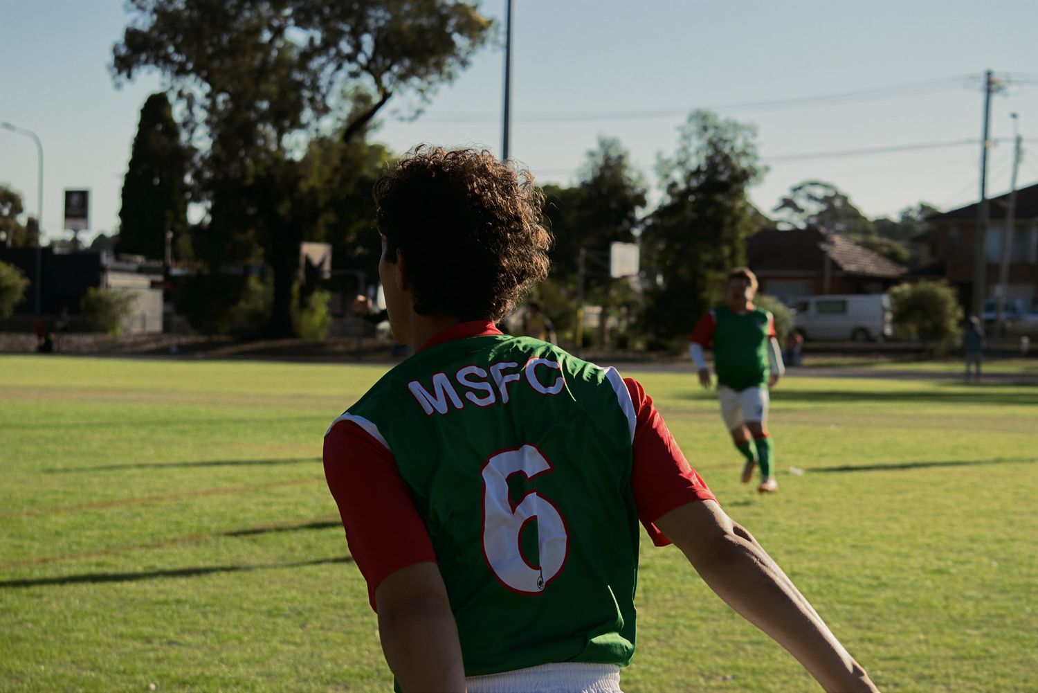 MSFC number 6 soccer player runs across a green field during an outdoor daytime match.