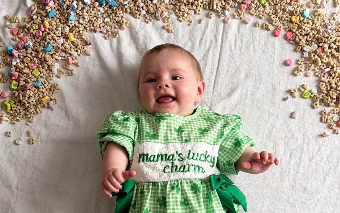 Laughing baby in mama's lucky charm dress with Lucky Charms cereal border.