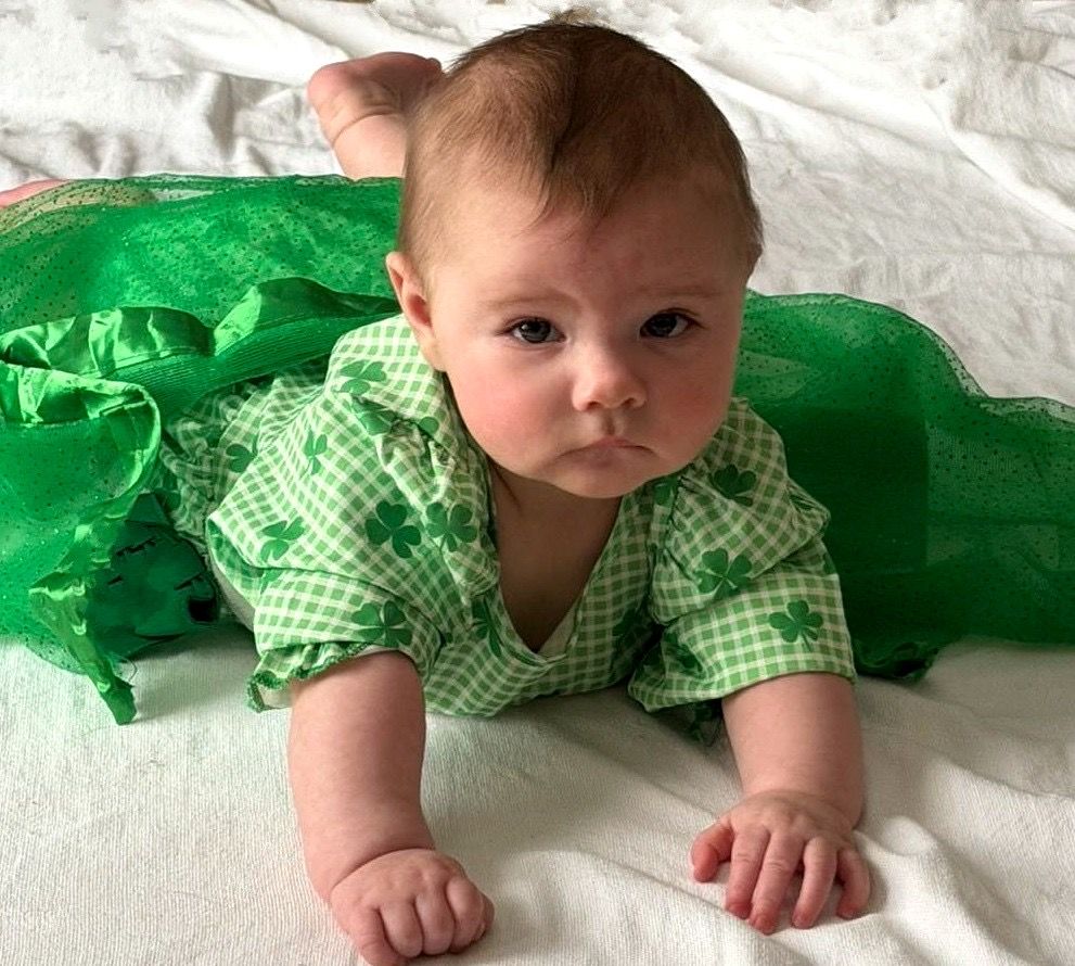 Baby in green shamrock outfit doing tummy time for St. Patrick's Day.