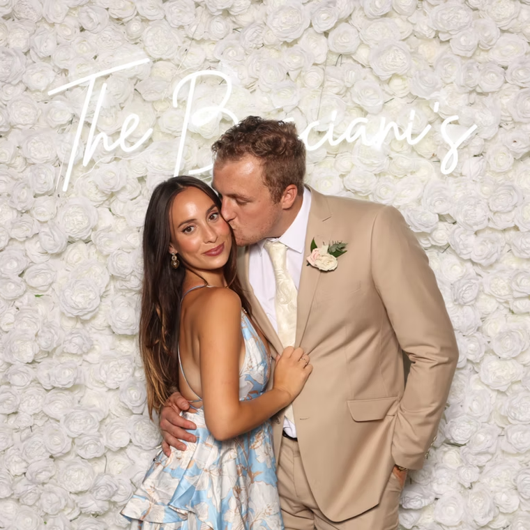 Couple in front of flower wall at photo booth.