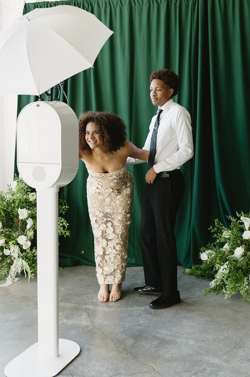 Couple using photo booth in front of green draped backdrop at Maryland Wedding