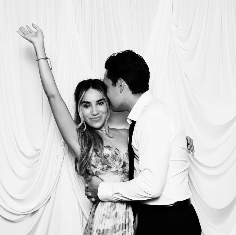 Couple in front of draped backdrop.