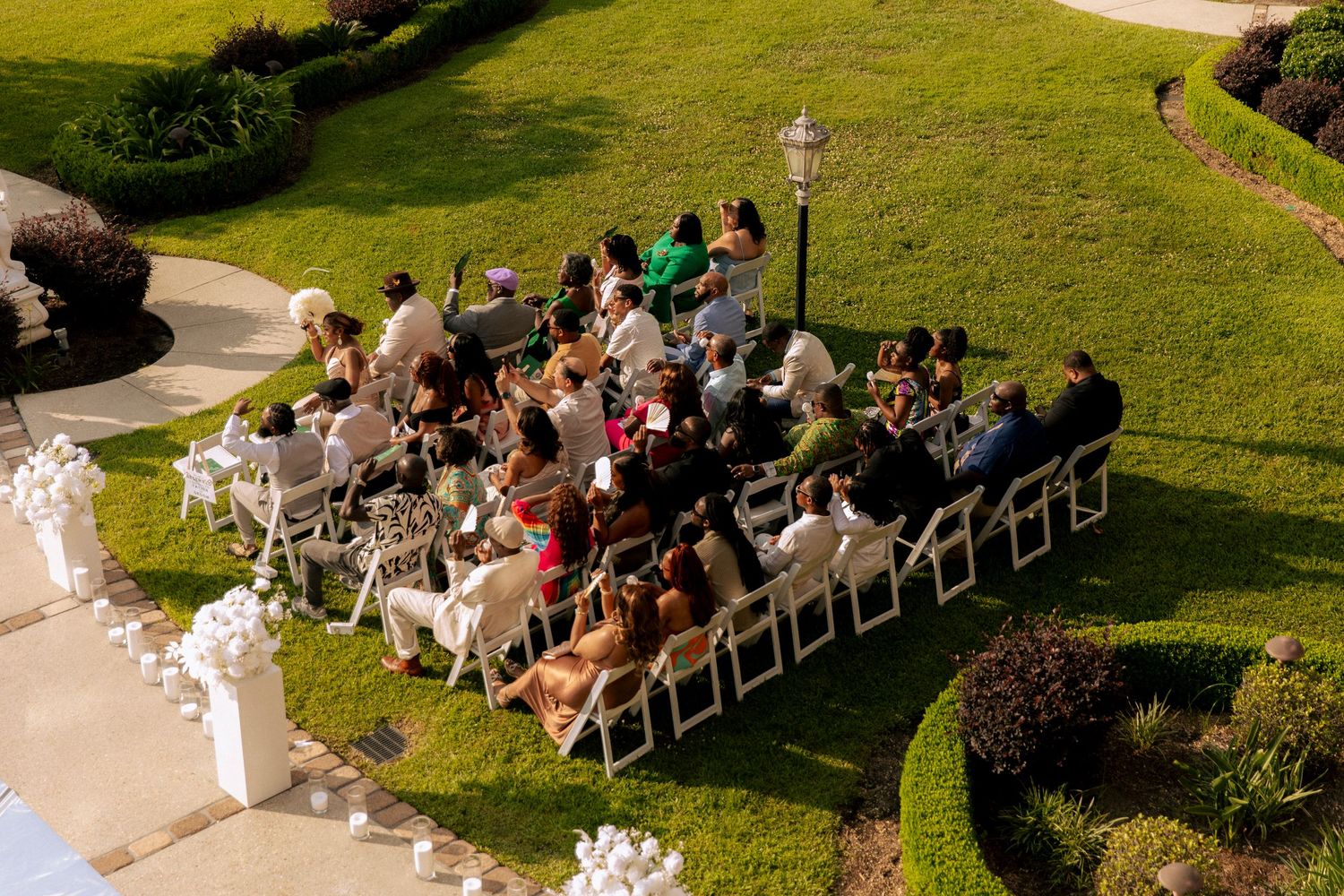 Aerial view of wedding ceremony seating arrangement on green lawn with curved walkway.