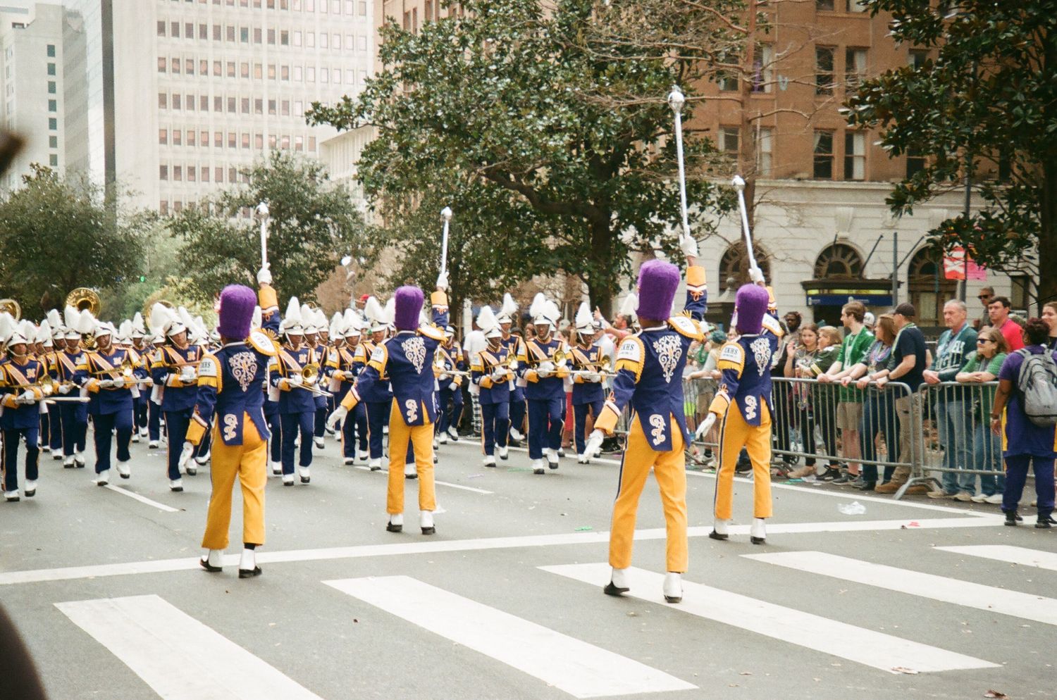 Line of performers in yellow pants walking in formation during a street parade.