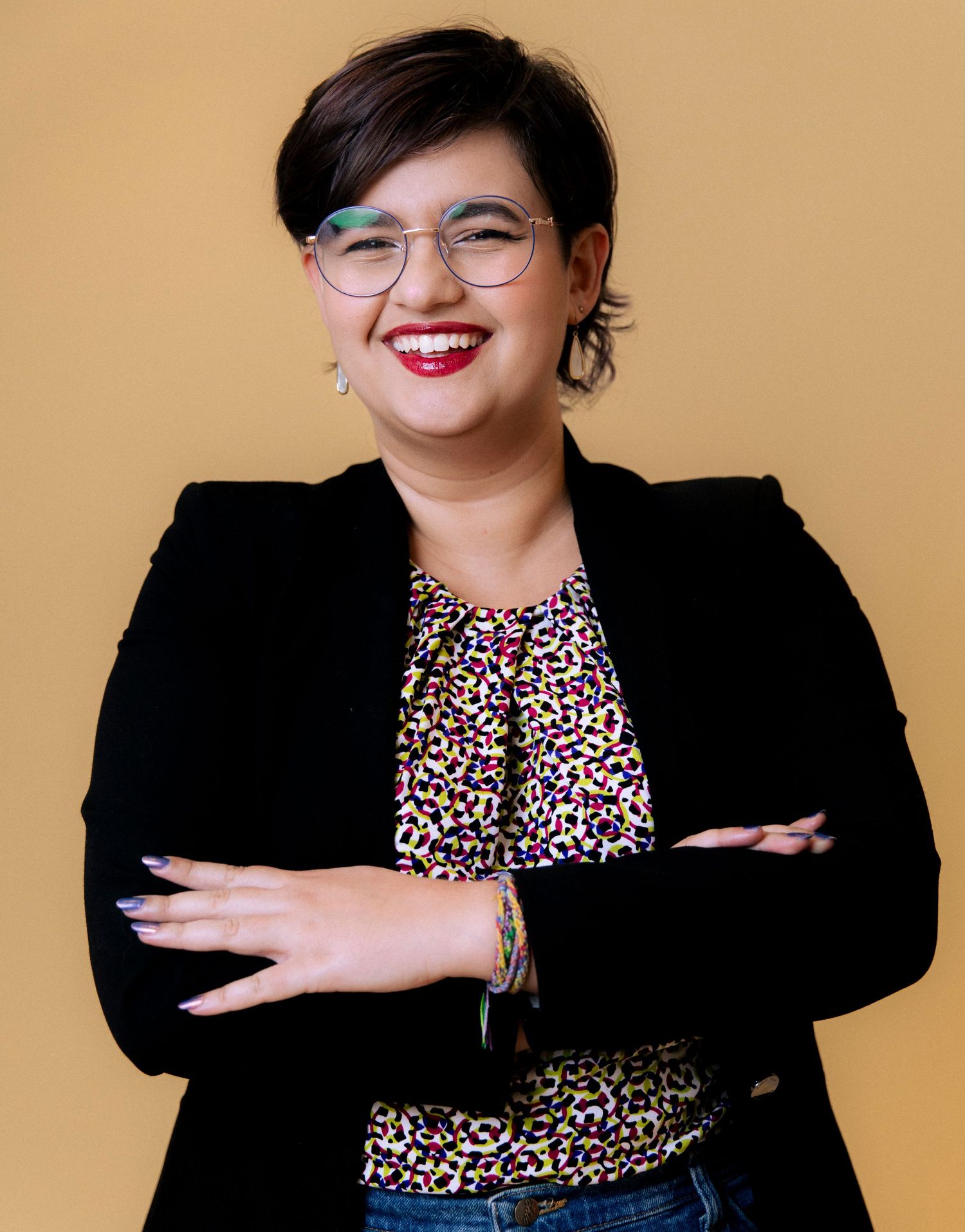 Person in black blazer and leopard print top strikes fun poses against beige background in photo series.