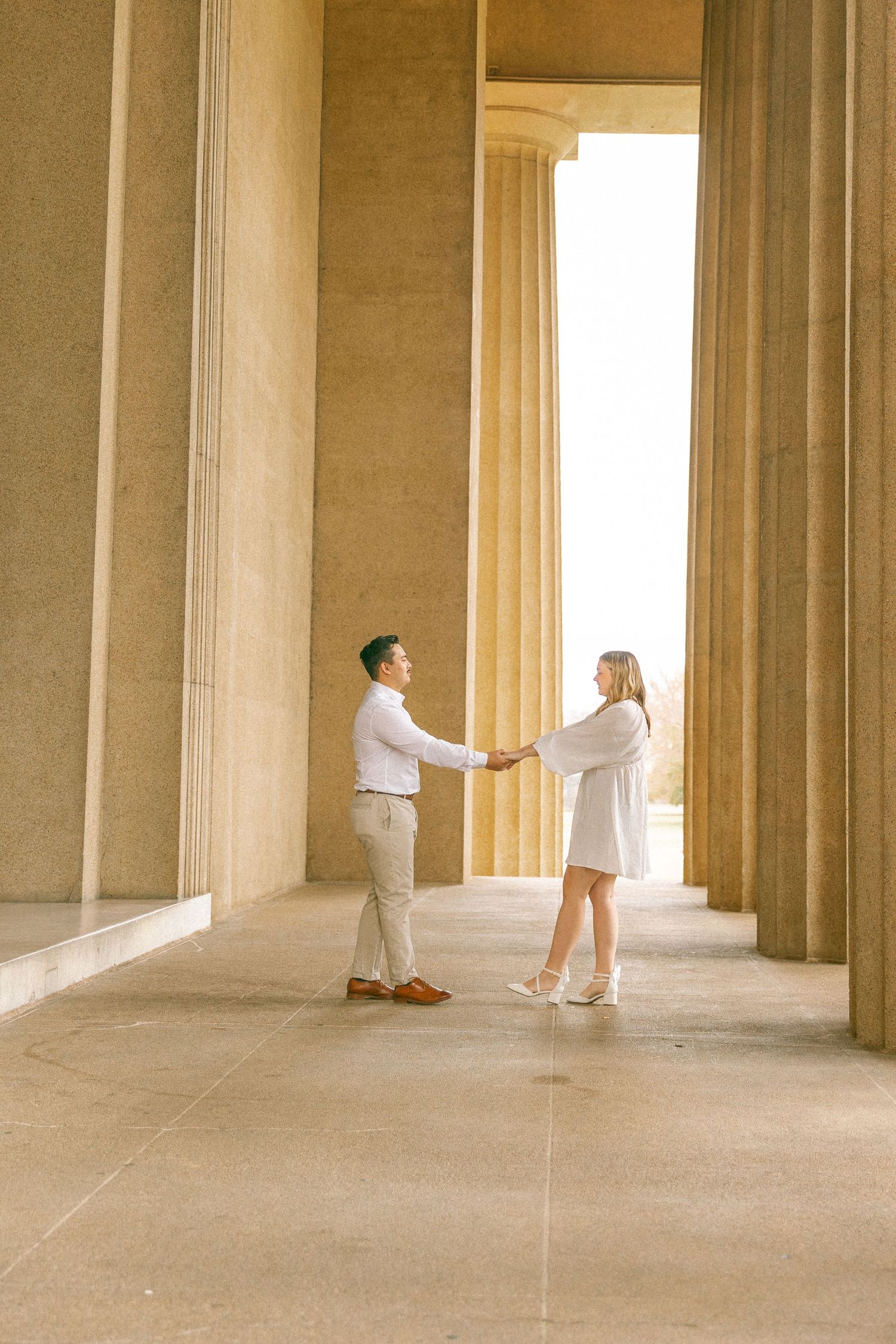 Couple holding hands between tall stone columns at the Lincoln Memorial in Washington D.C.