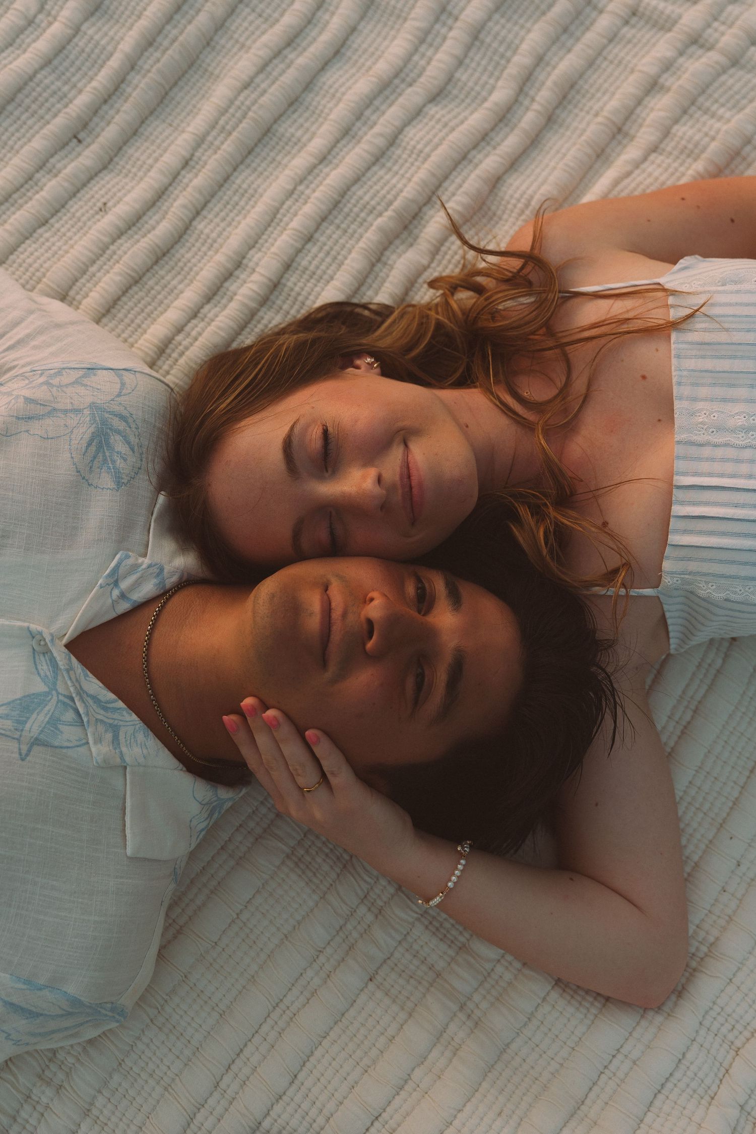 Couple lies together on blanket looking up peacefully during romantic outdoor photo session.