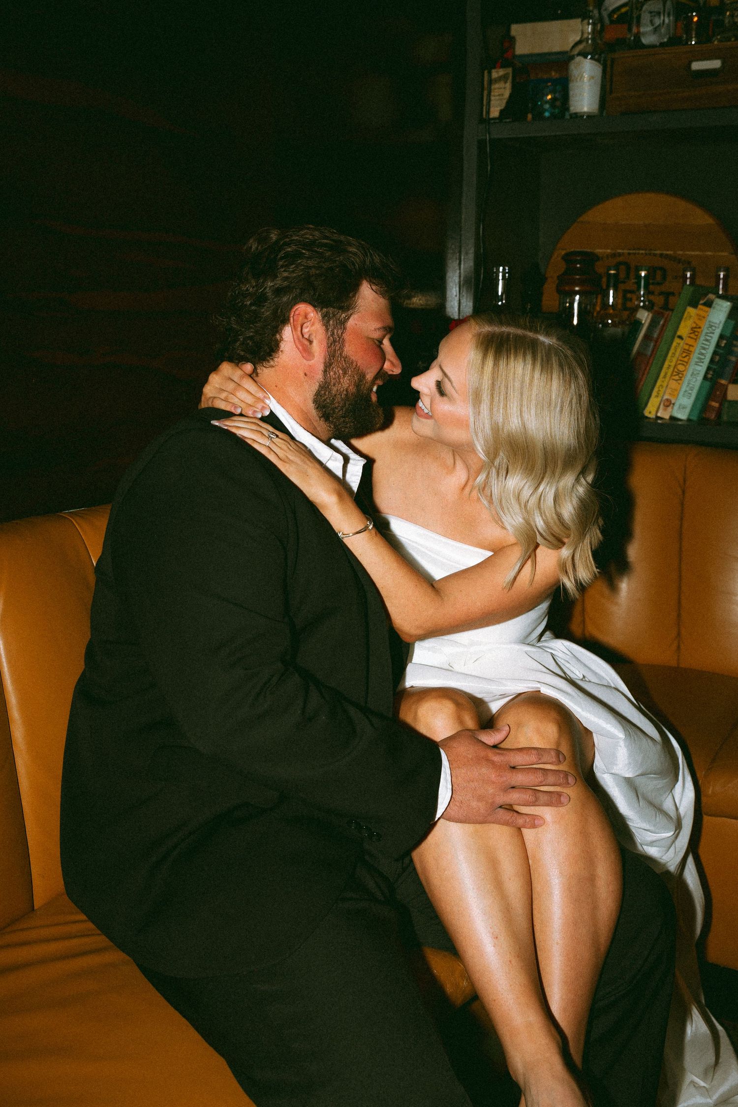 Couple sharing an intimate romantic moment sitting together on a leather sofa in a dimly lit bar.