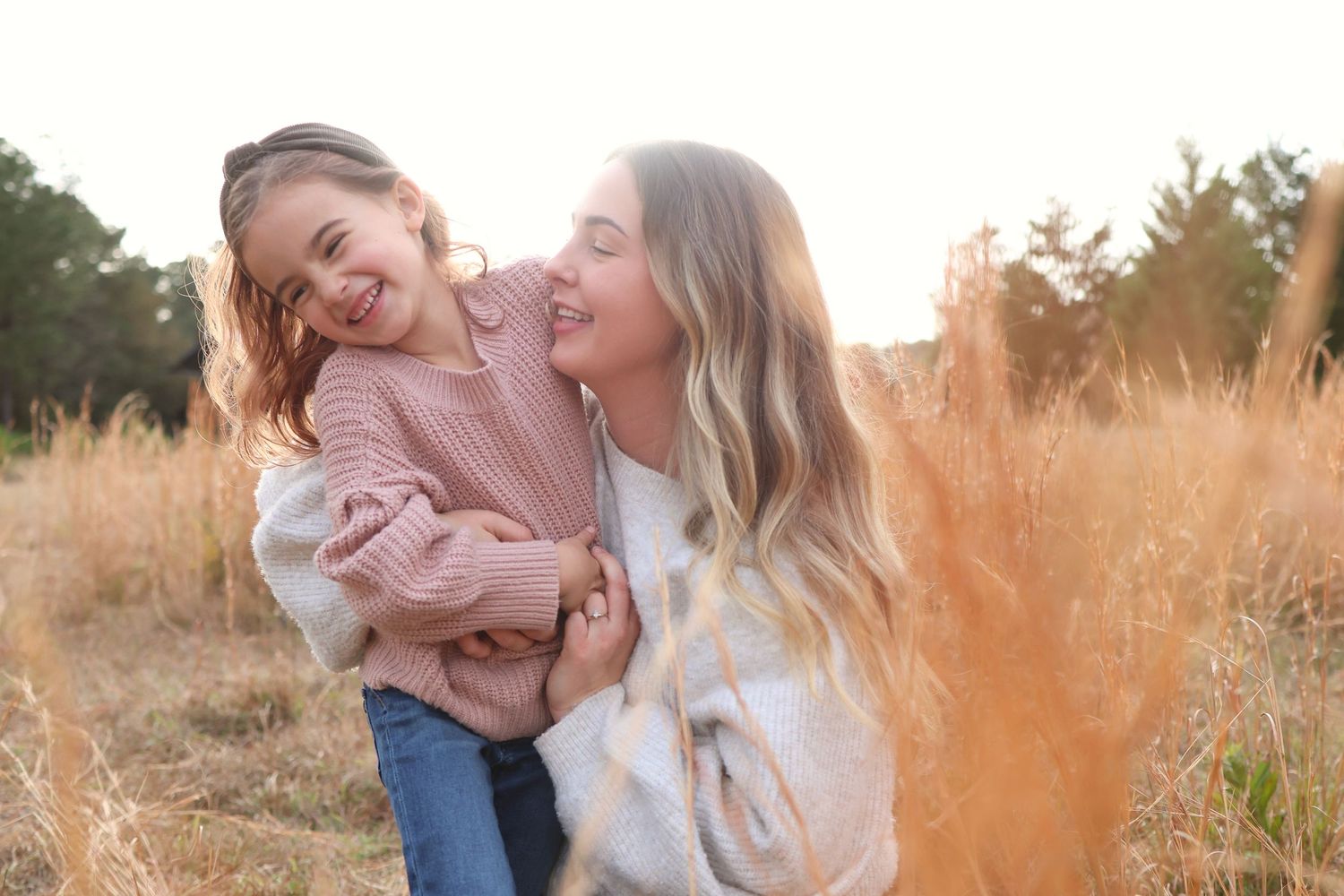 portrait of a mother and daughter playing in a field with long grass