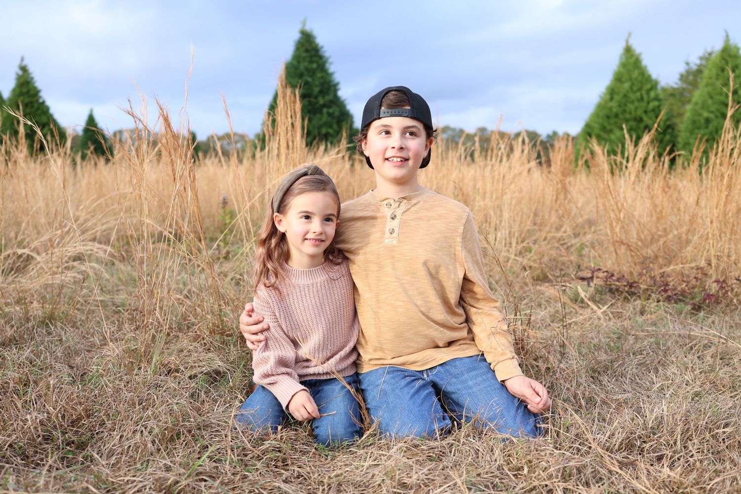 portrait of two children sitting together in tall grass