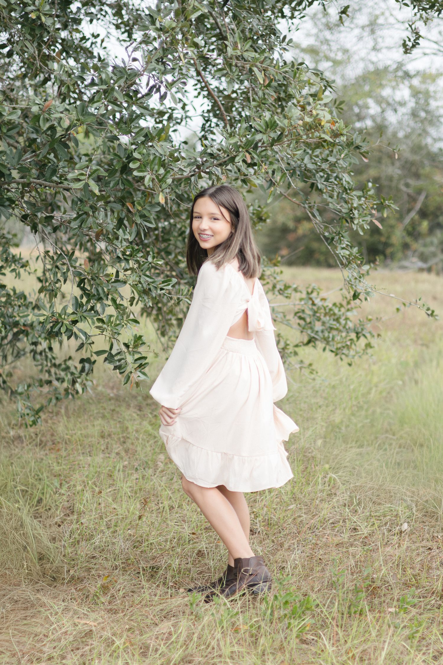 Portrait of a tween girl spinning near a tree in a field