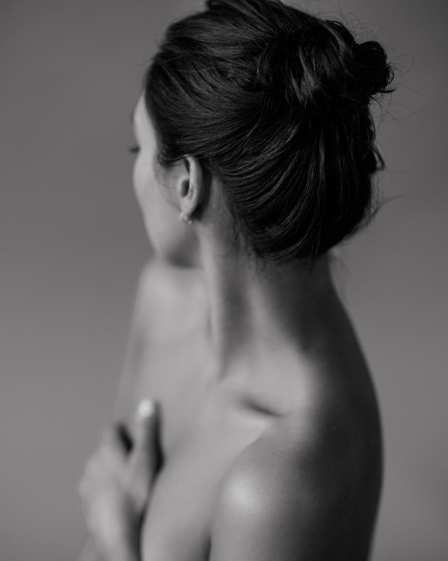 Black and white fine art portrait of a woman with upswept hair, photographed from behind in elegant pose.
