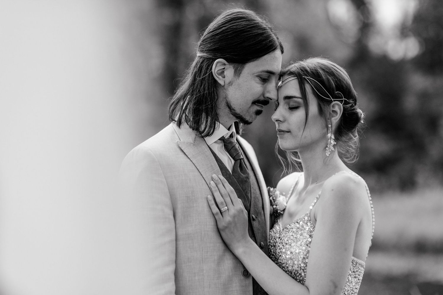 Black and white wedding photo of bride and groom sharing an intimate moment, foreheads touching tenderly.