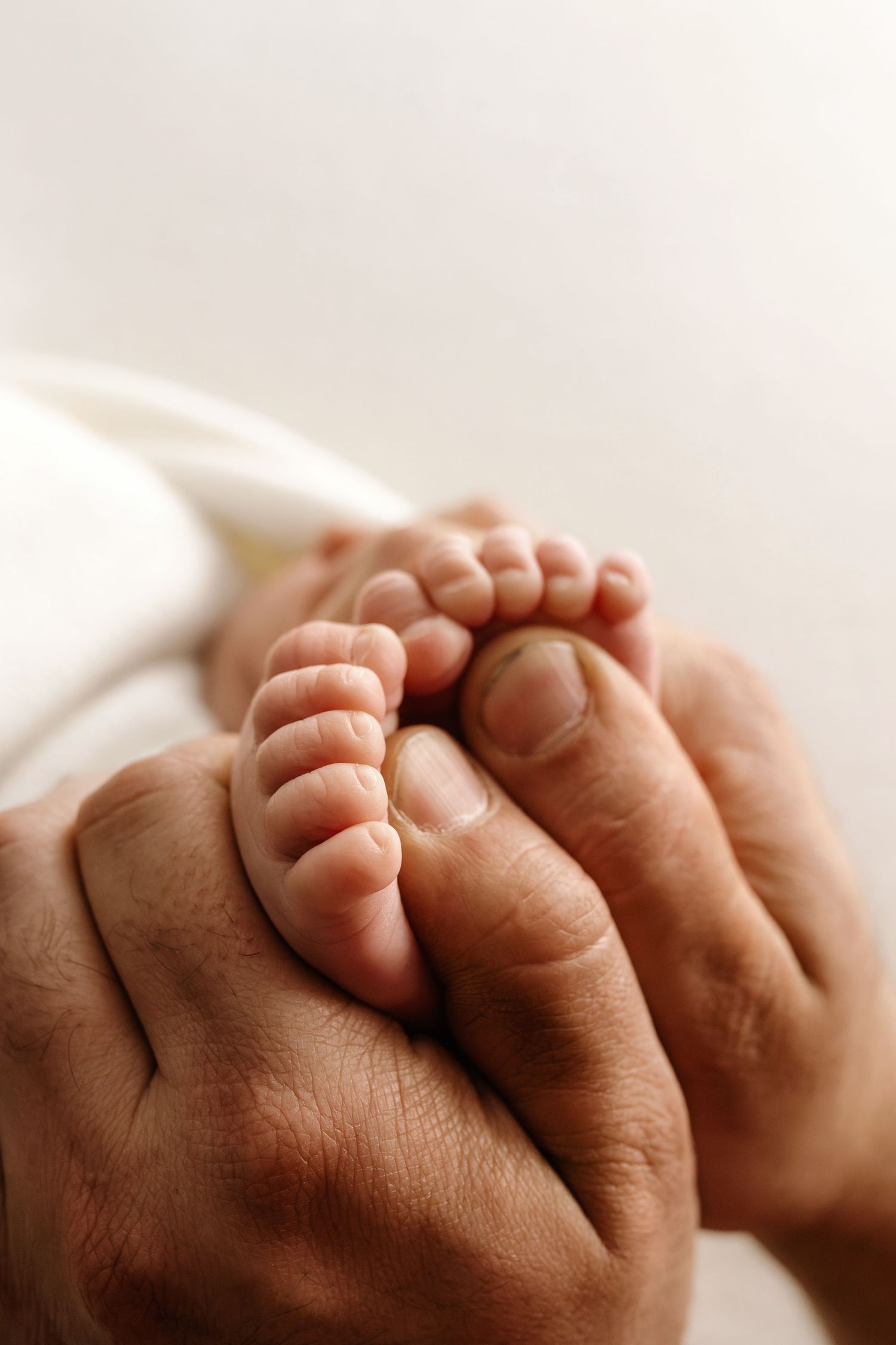 A close-up photo of tiny newborn baby feet being gently held in adult hands.