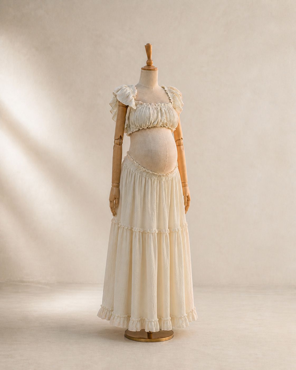 Ivory cream maternity two-piece set with ruffled crop top and tiered maxi skirt displayed on a dress form mannequin.