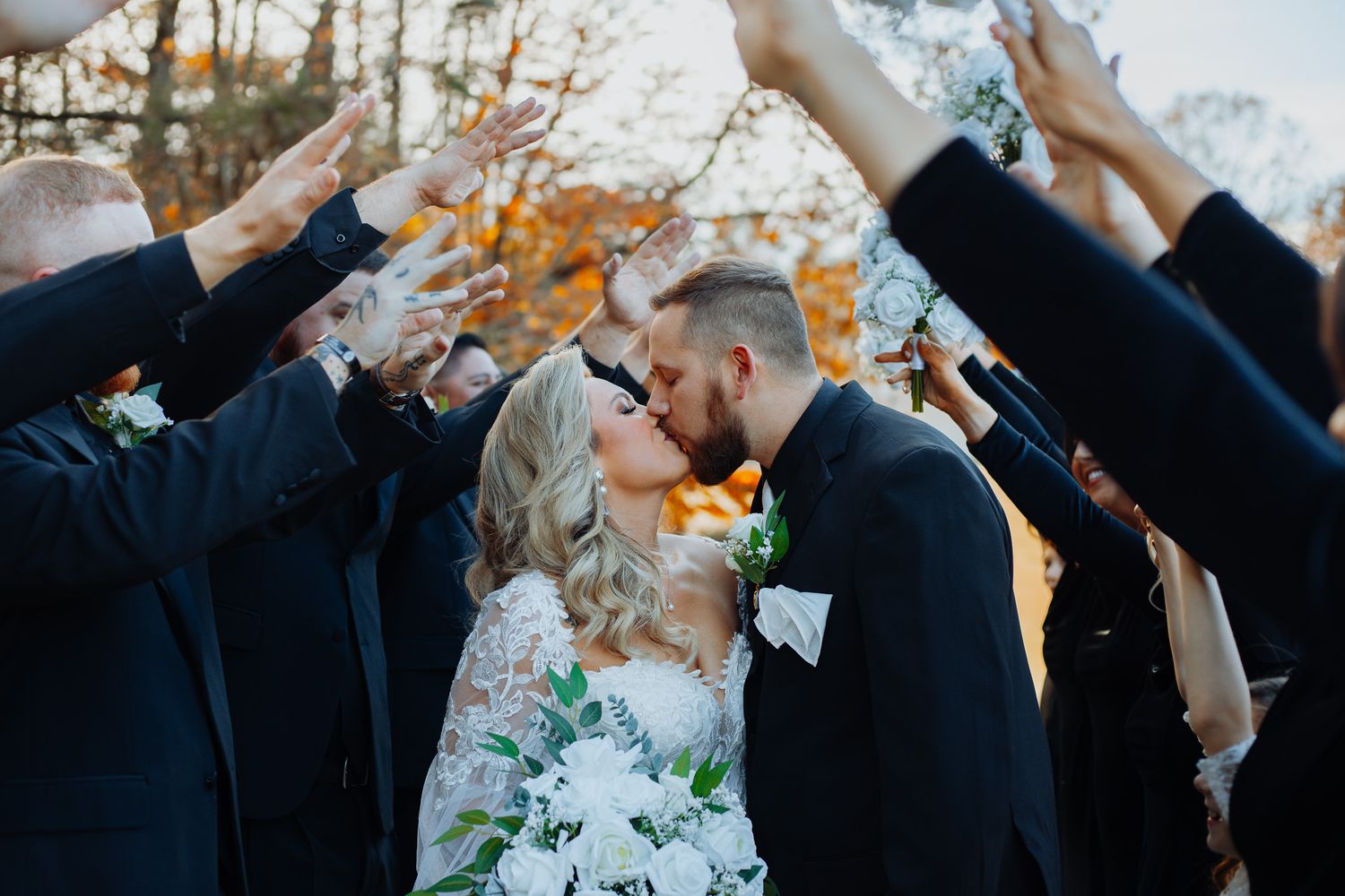 Wedding party poses playfully on the ground during fall outdoor photo session.