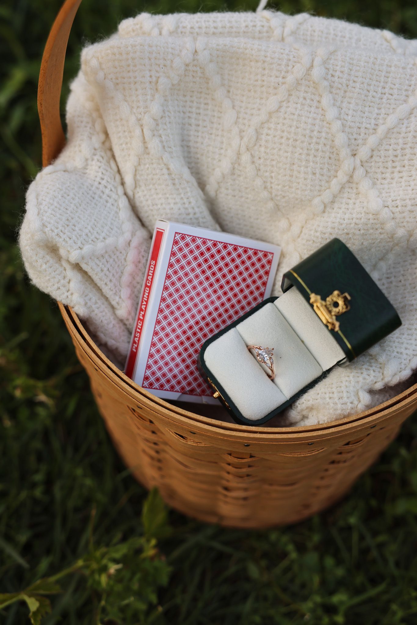Woven basket containing notebooks and small accessories on grass.