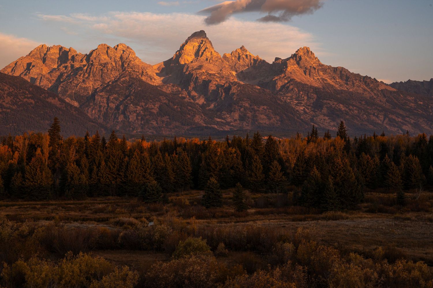 Rugged mountain peaks glow orange at sunset in Grand Teton National Park.