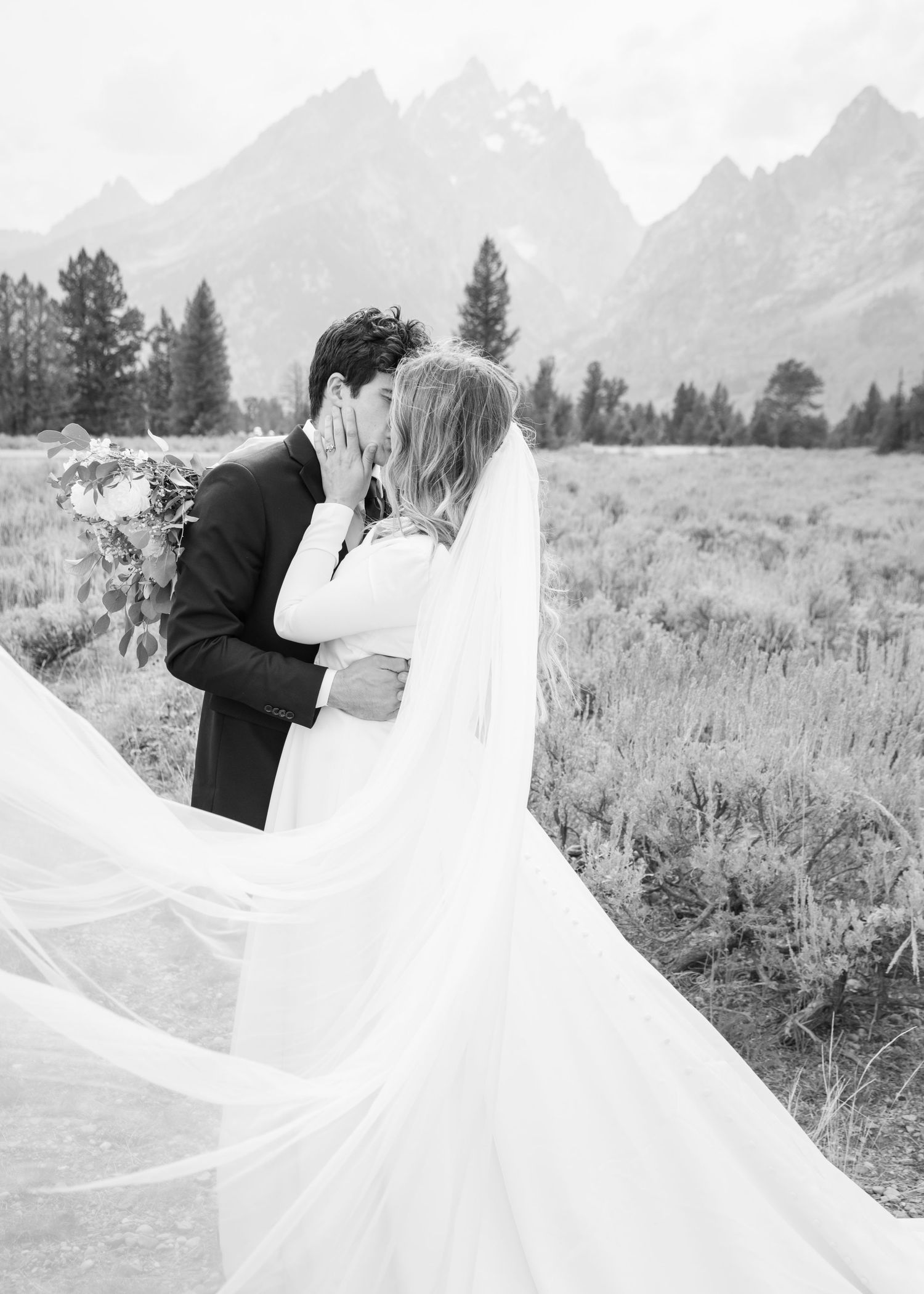 A romantic wedding moment captured in black and white against the dramatic Teton mountain backdrop.