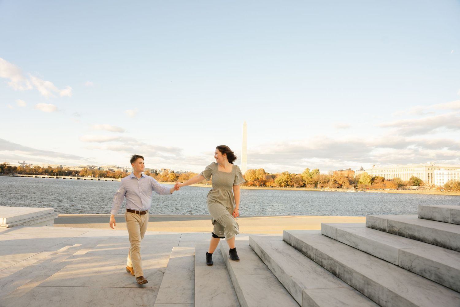 Two people walk along concrete steps at sunset near a beach with warm golden lighting.