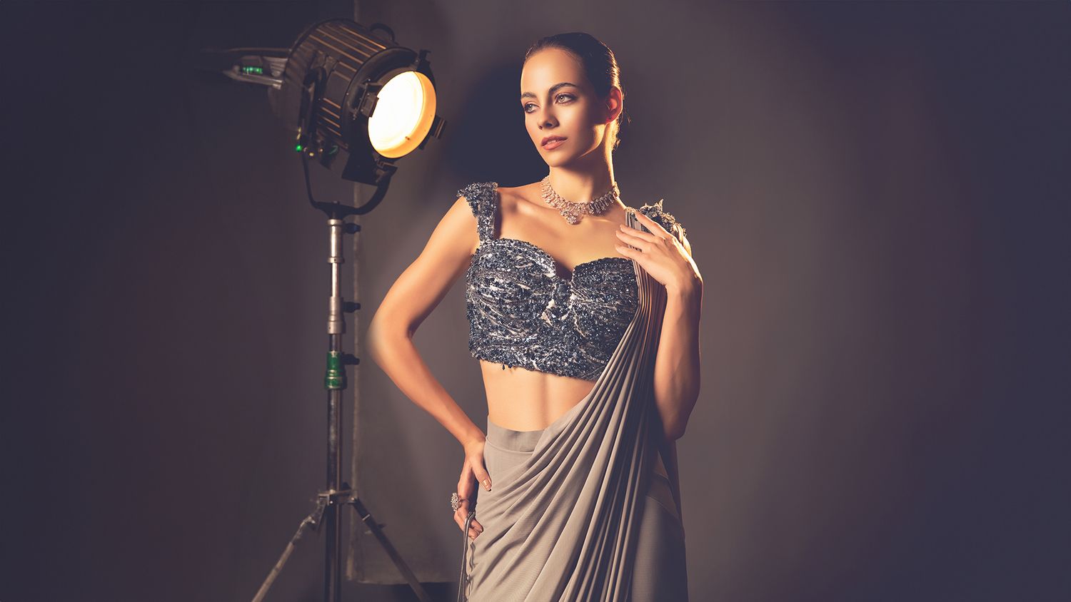 Elegant Indian saree fashion photoshoot with professional studio lighting and dark dramatic background.