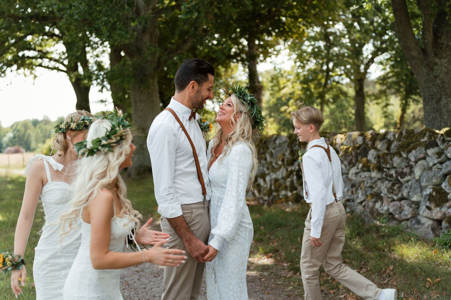 Wedding couple shares intimate moment under large tree branches during outdoor summer ceremony.