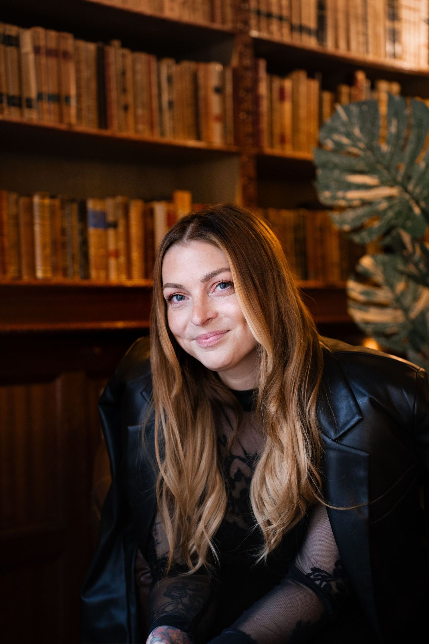 Portrait in vintage library setting with warm lighting and wooden bookshelves.