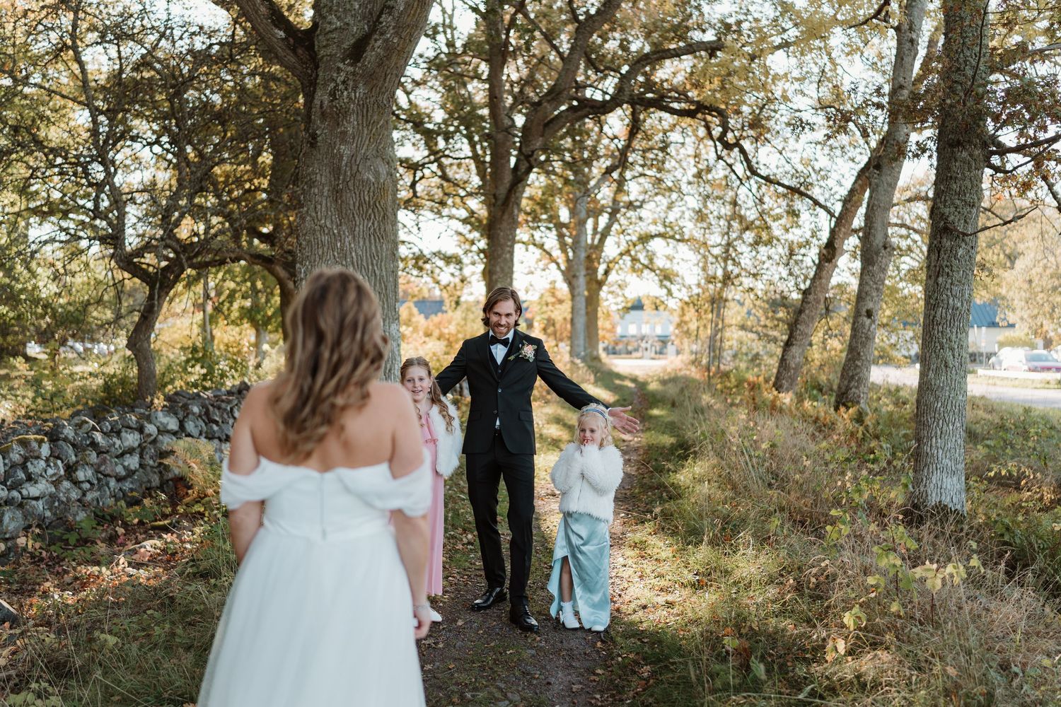 A couple in wedding attire shares a romantic moment together in a sunlit wooded area during their outdoor ceremony.