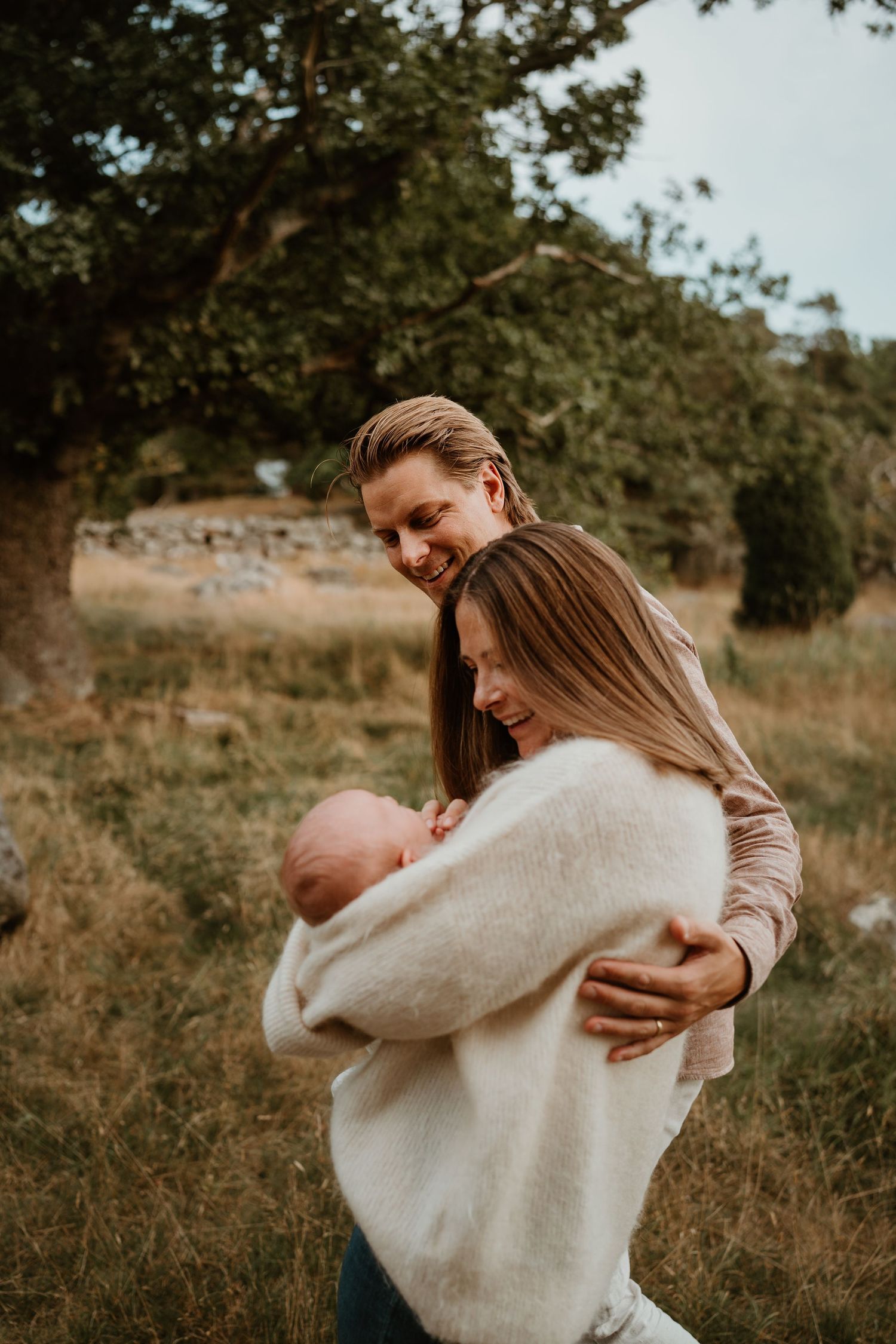 Two people share a tender embrace outdoors in a natural setting during golden hour.