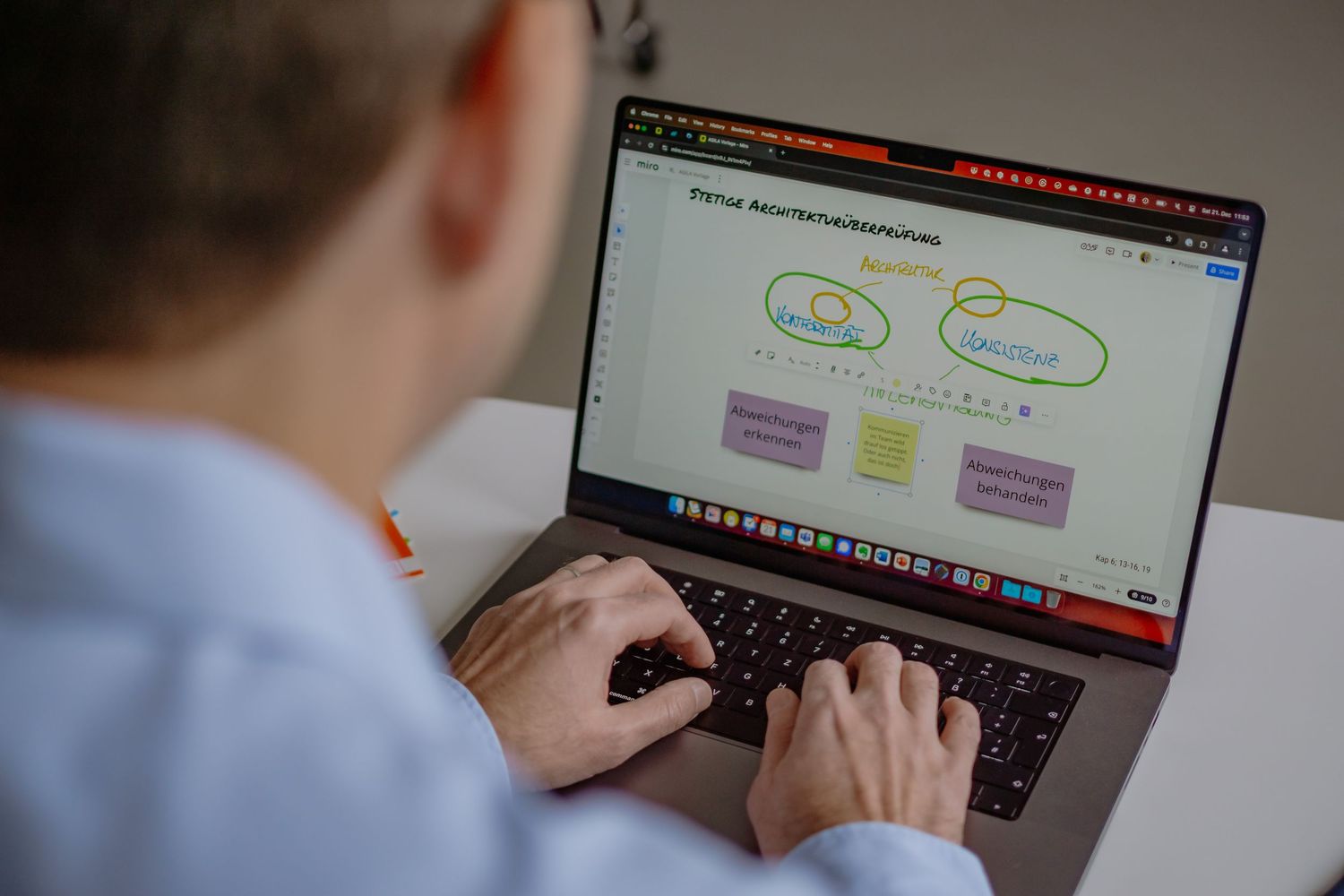 A professional working on a laptop displaying a digital architecture diagram with cloud-based workflow visualization.
