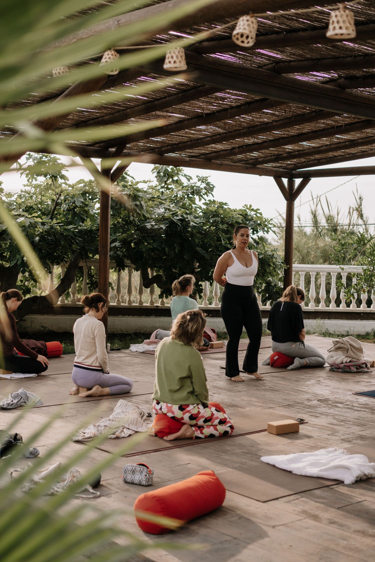 Group yoga class on outdoor terrace with instructor guiding students on mats.