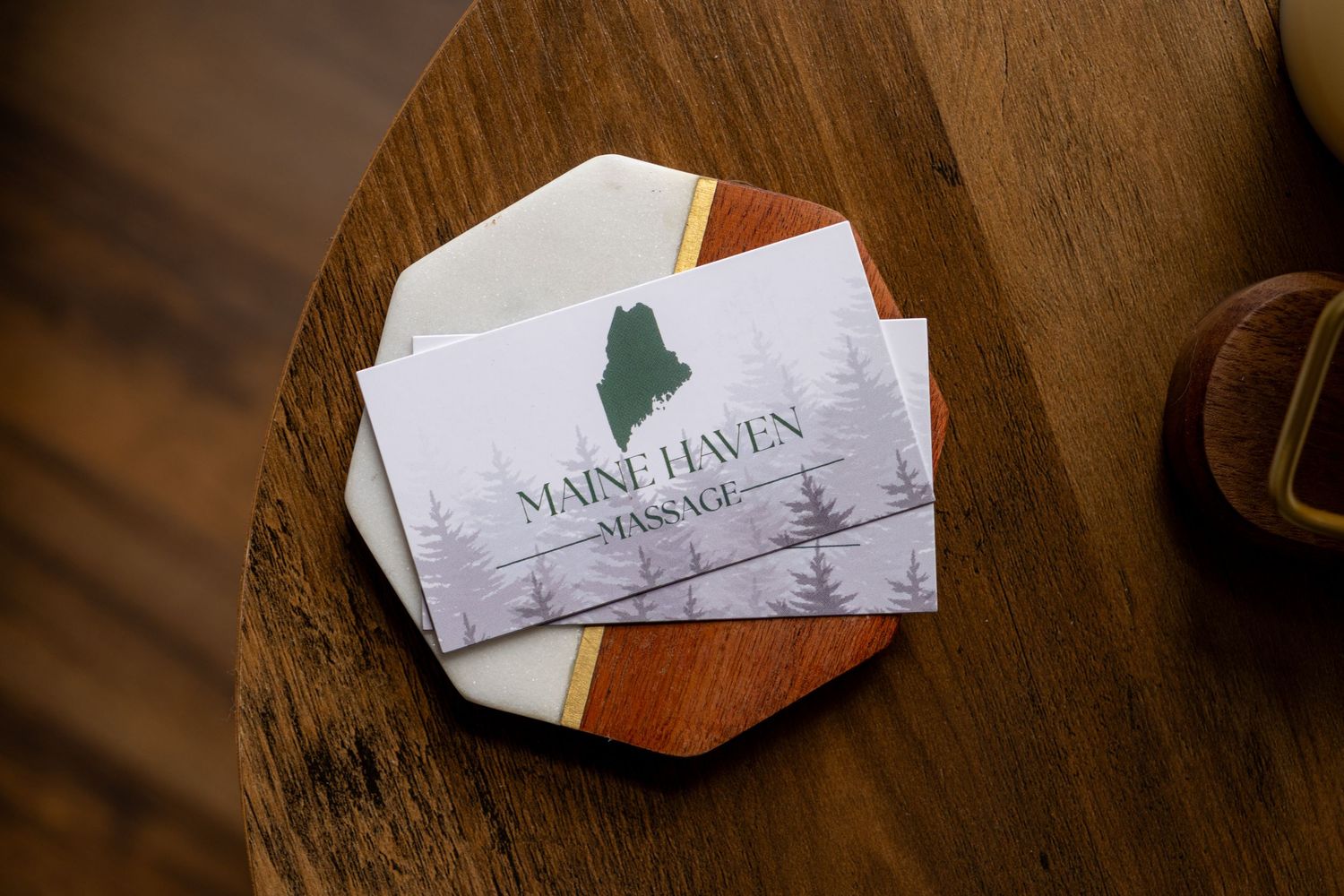 Branding detail photo of Maine Haven Massage business cards on a wooden table.