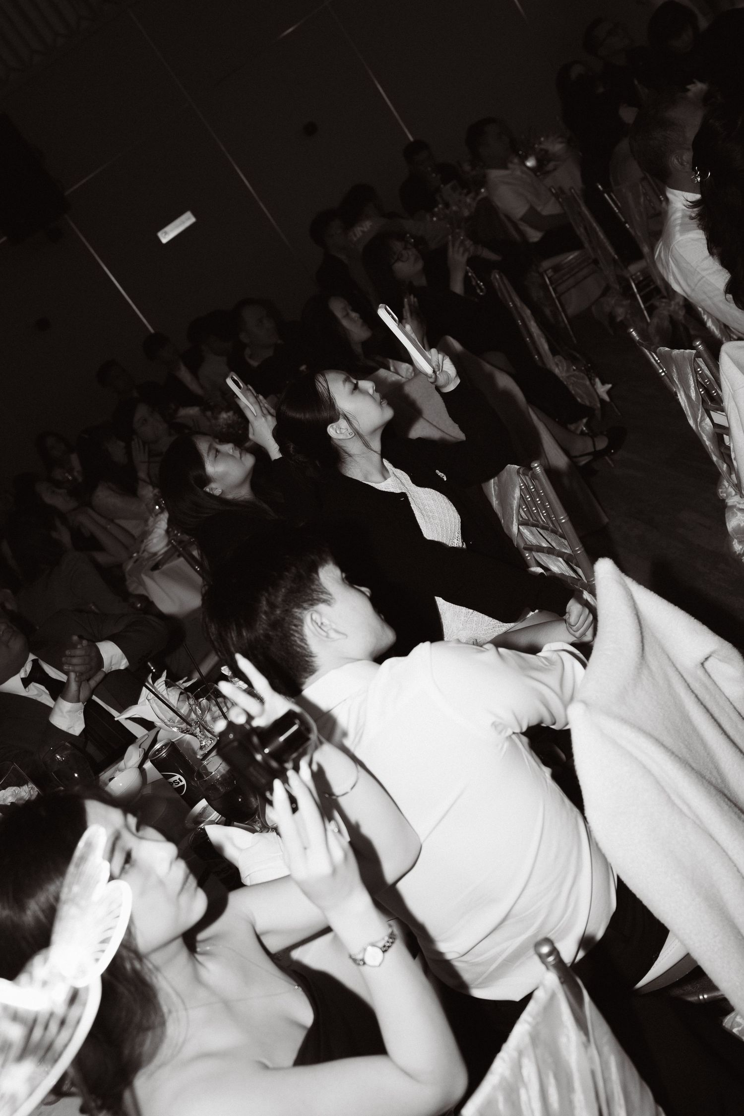 Wedding guests and photographer capture moments during a lively black and white wedding reception celebration.