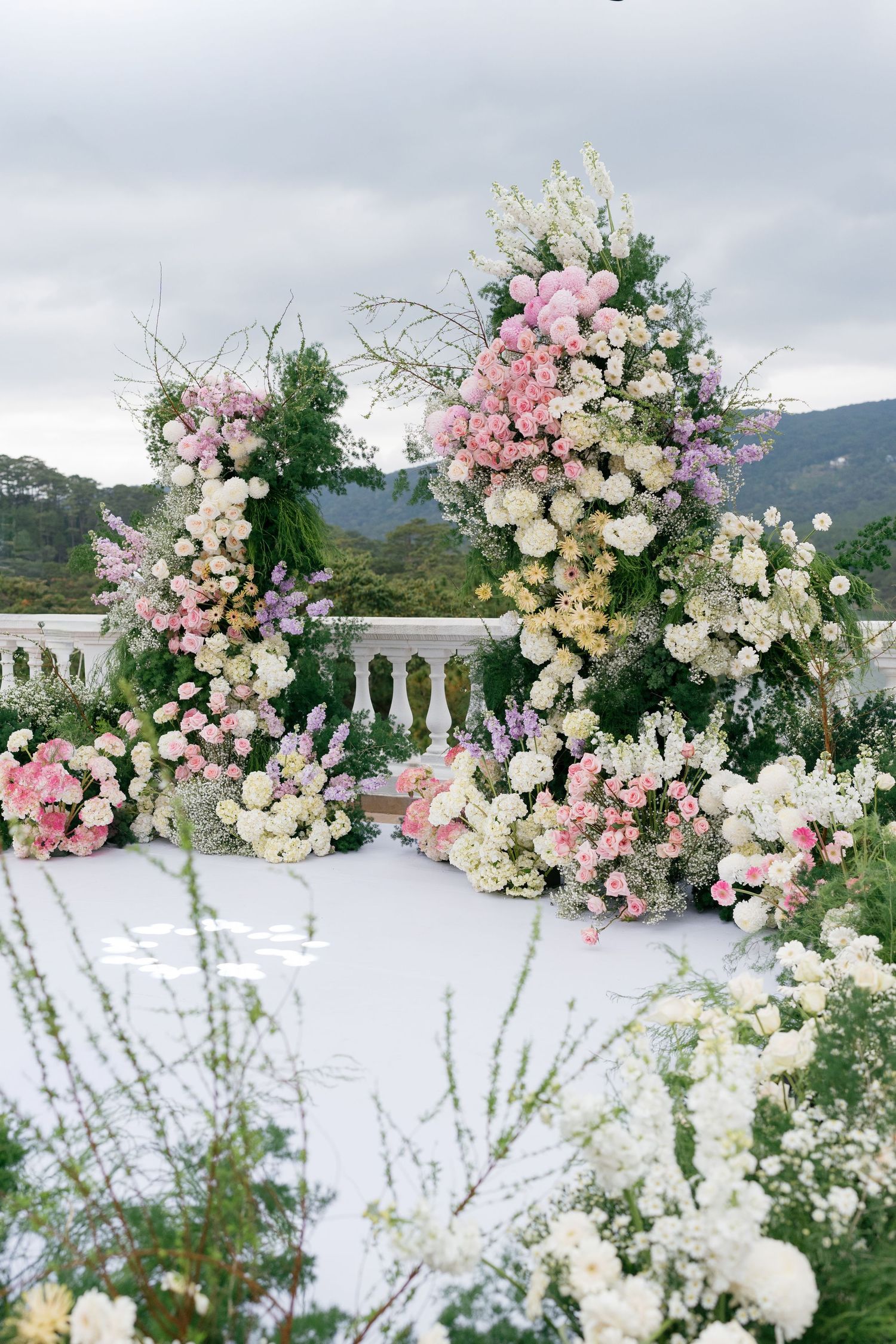 Elegant outdoor wedding arch adorned with lush pink and white floral arrangements against a scenic mountain backdrop.