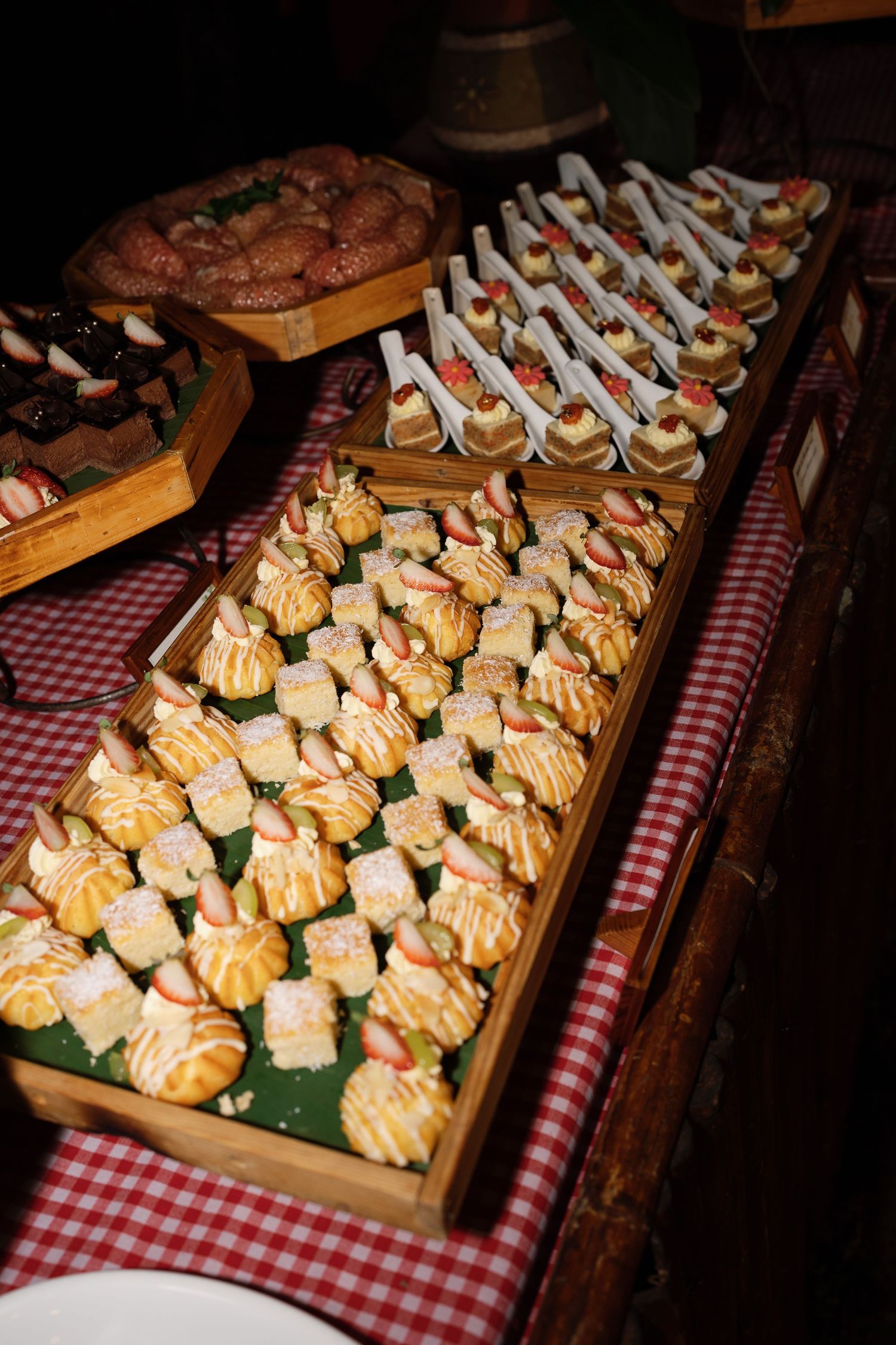 Elegant wedding reception dessert table with assorted pastries and canapes in wooden trays.