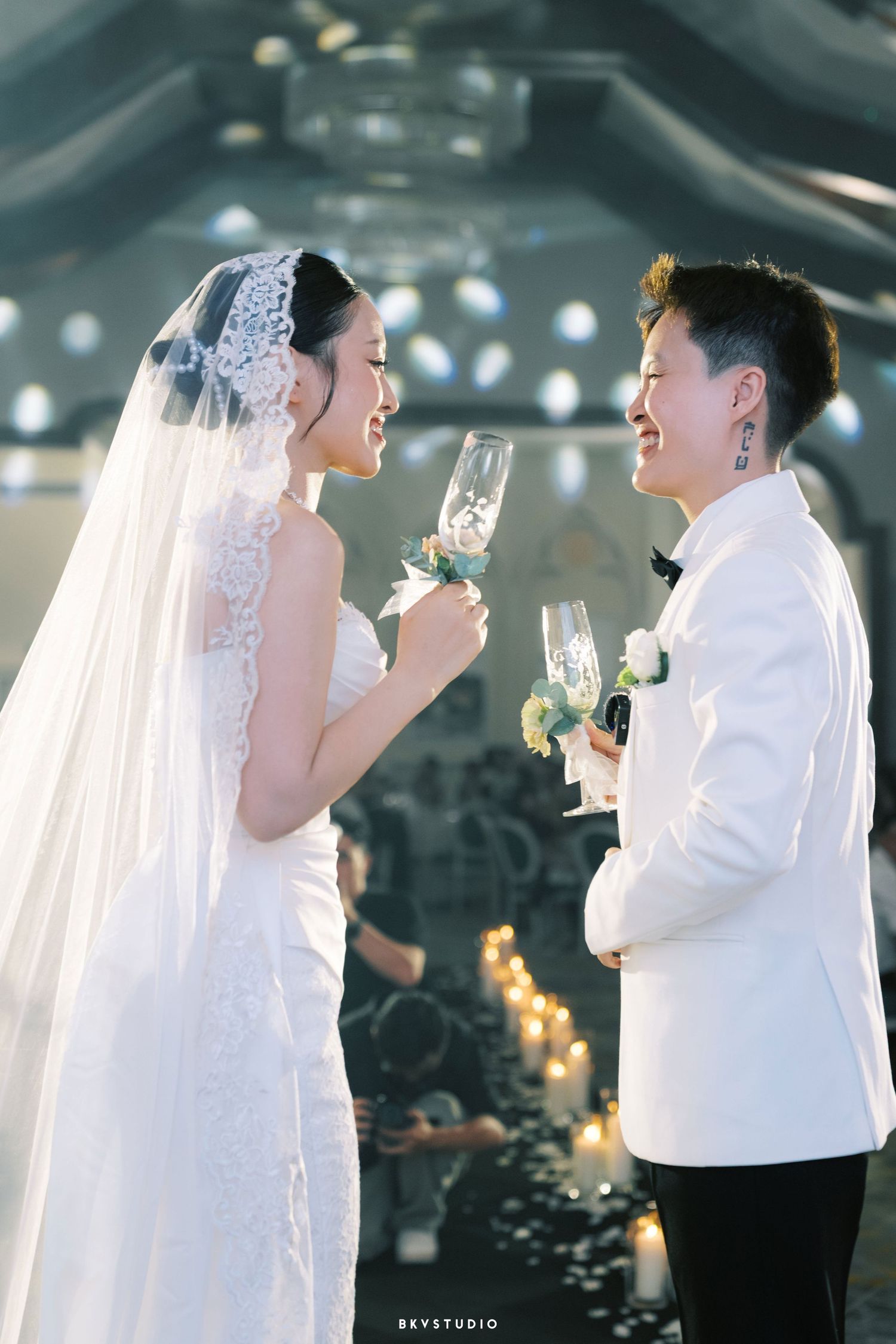 Bride and groom toasting with champagne glasses at elegant wedding ceremony, wearing white dress and tuxedo.