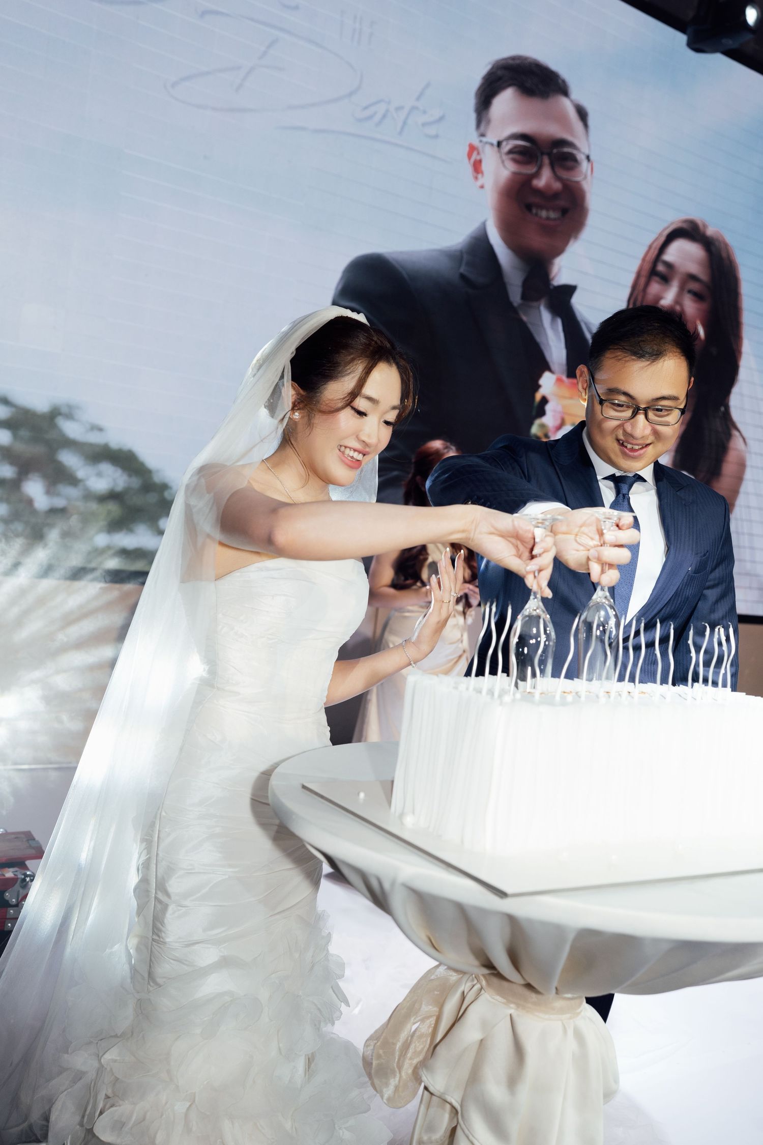 Bride and groom cutting their white wedding cake together at elegant reception ceremony.