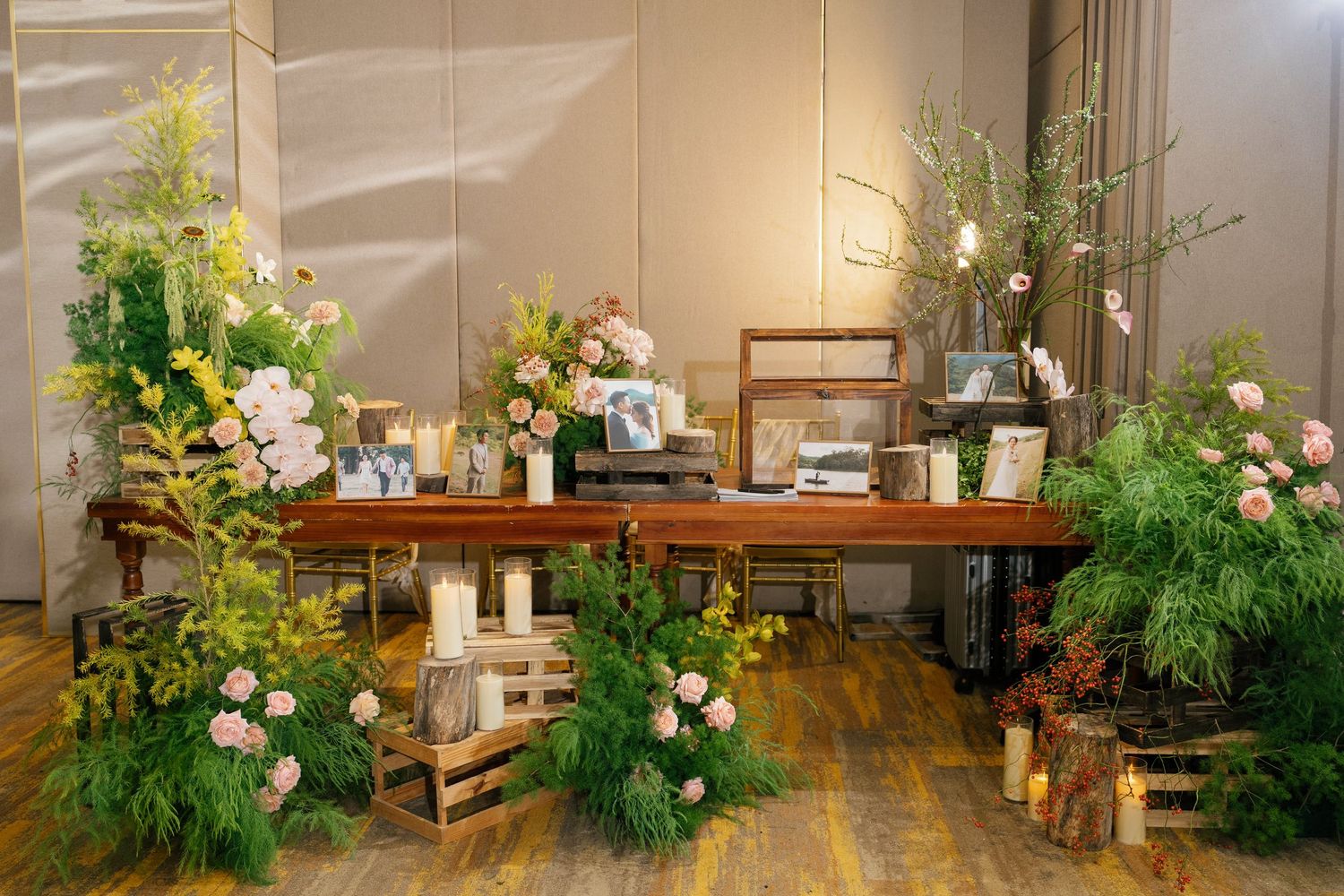 Elegant rustic wedding reception table surrounded by lush greenery and pink floral arrangements.