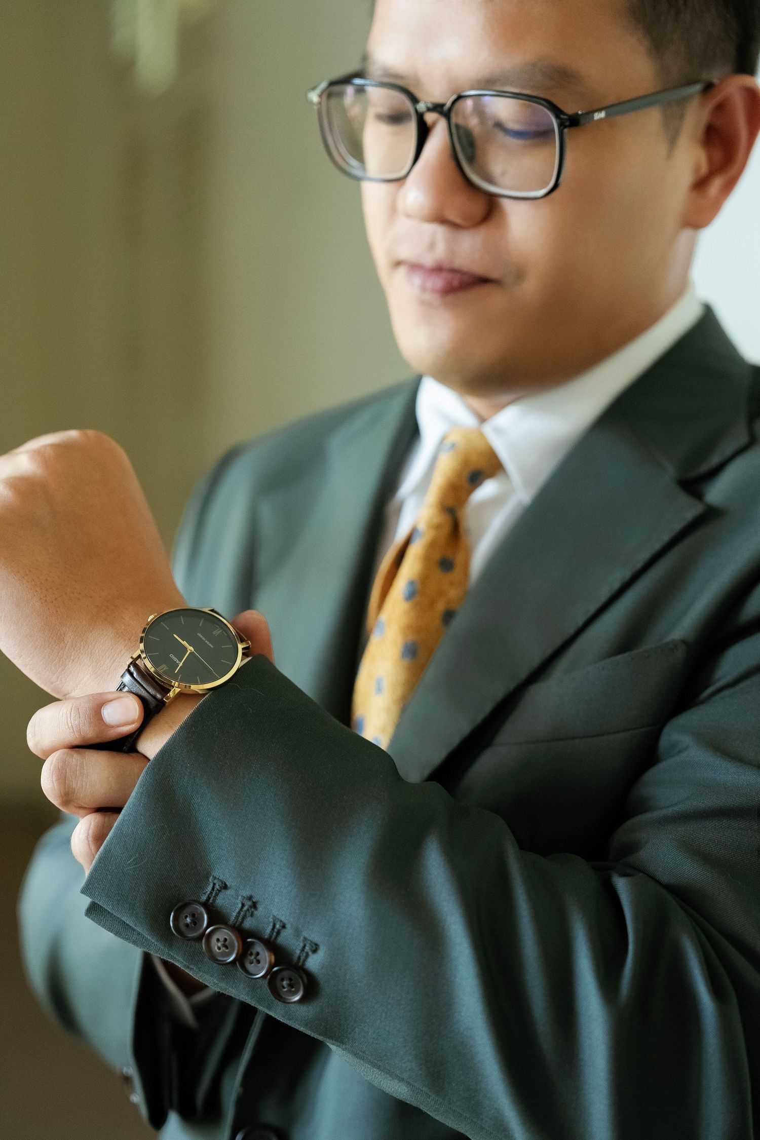 Businessman in gray suit checking luxury watch while adjusting cufflinks.