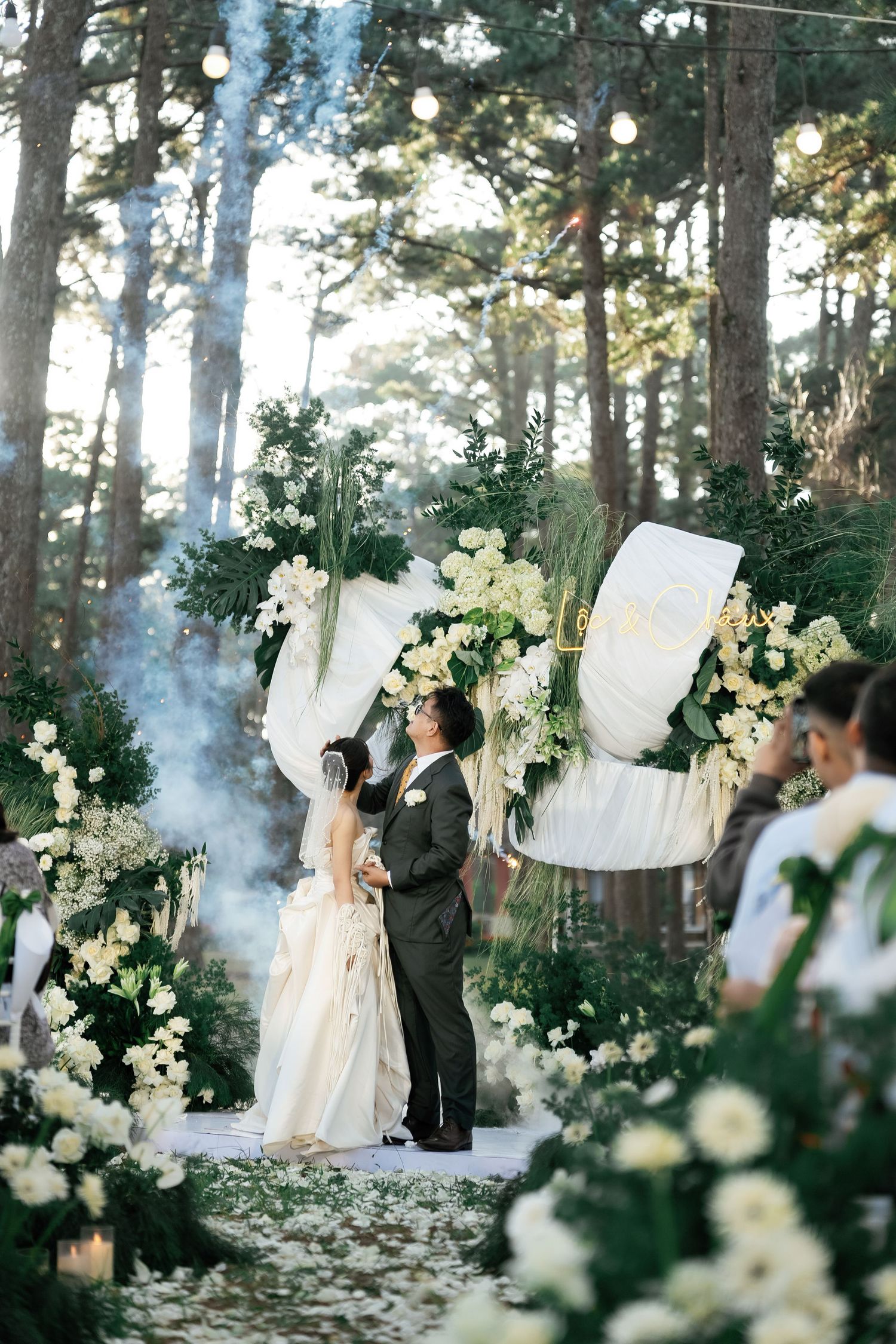 Couple sharing first dance at romantic outdoor forest wedding ceremony.