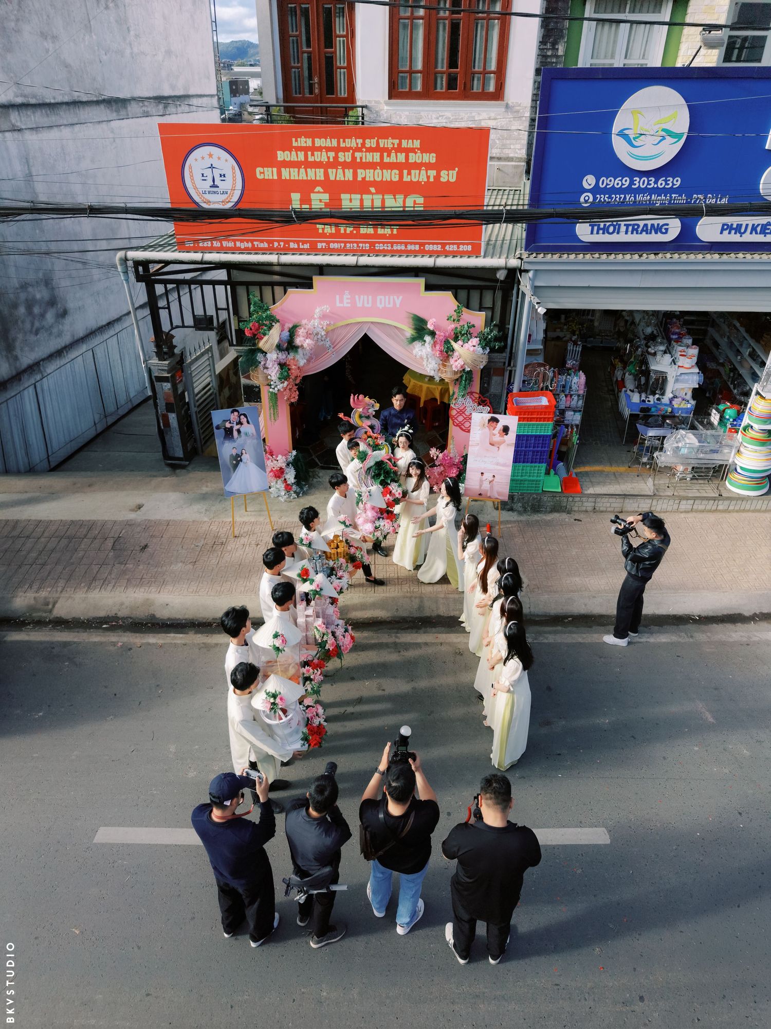 Aerial view of a Vietnamese wedding procession outside a decorated venue on a busy street.