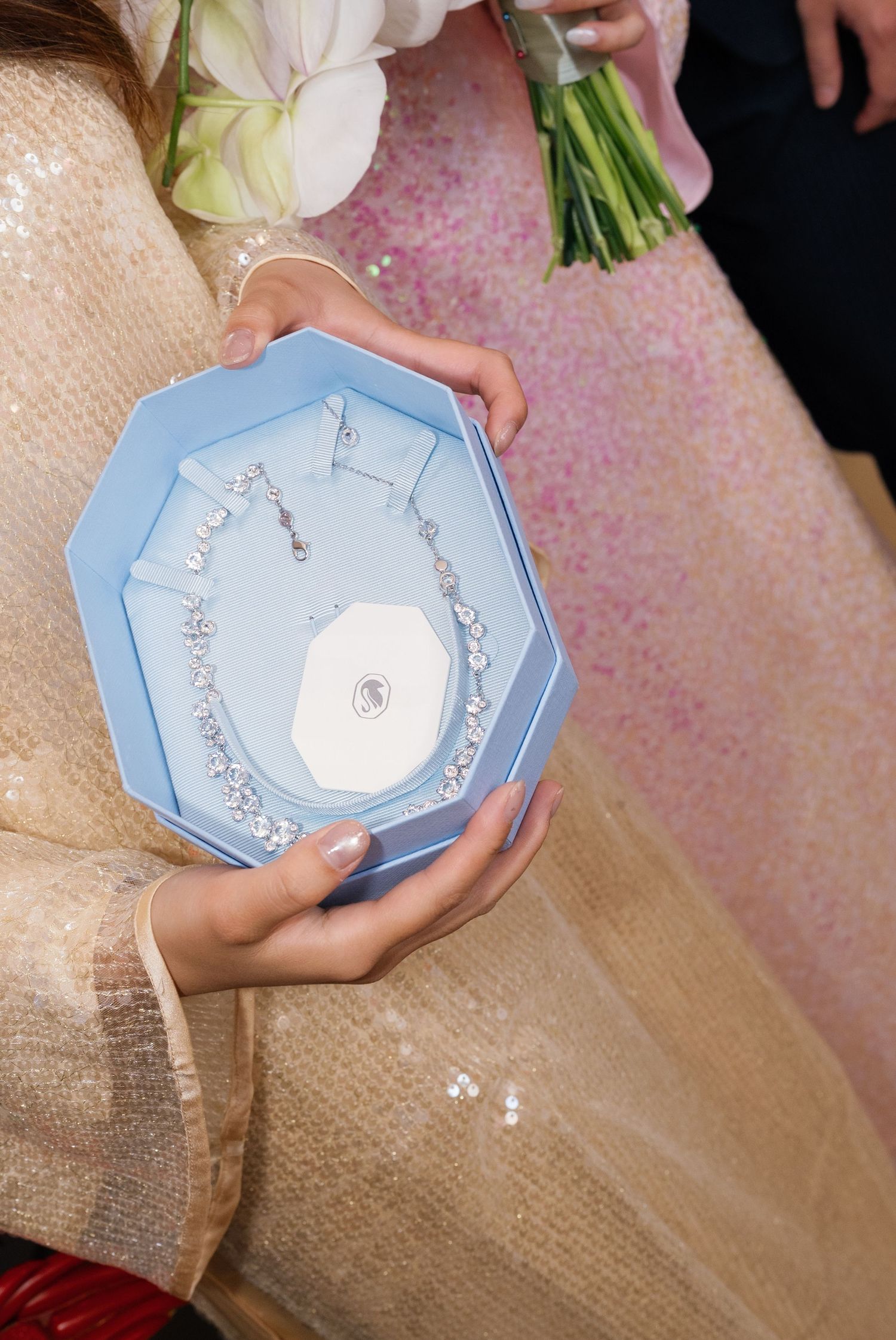 Diamond necklace and earrings displayed in a blue octagonal jewelry gift box.