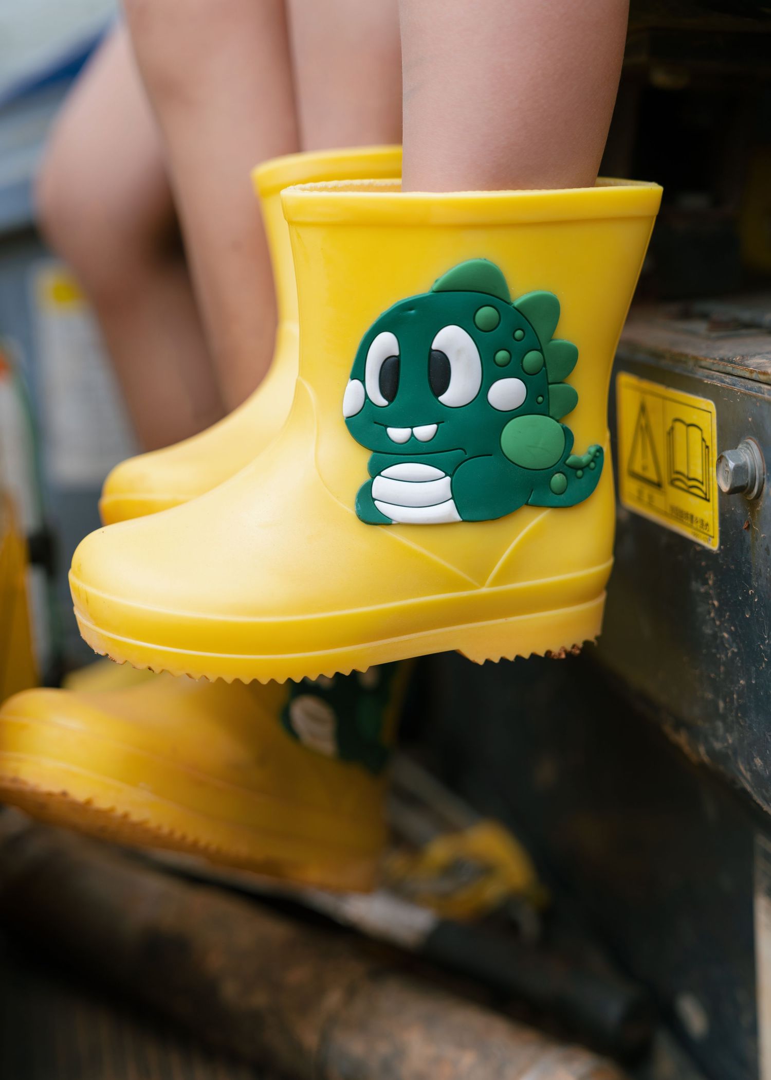 Yellow kids rain boots featuring a cute green dinosaur character design, perfect for rainy day adventures.