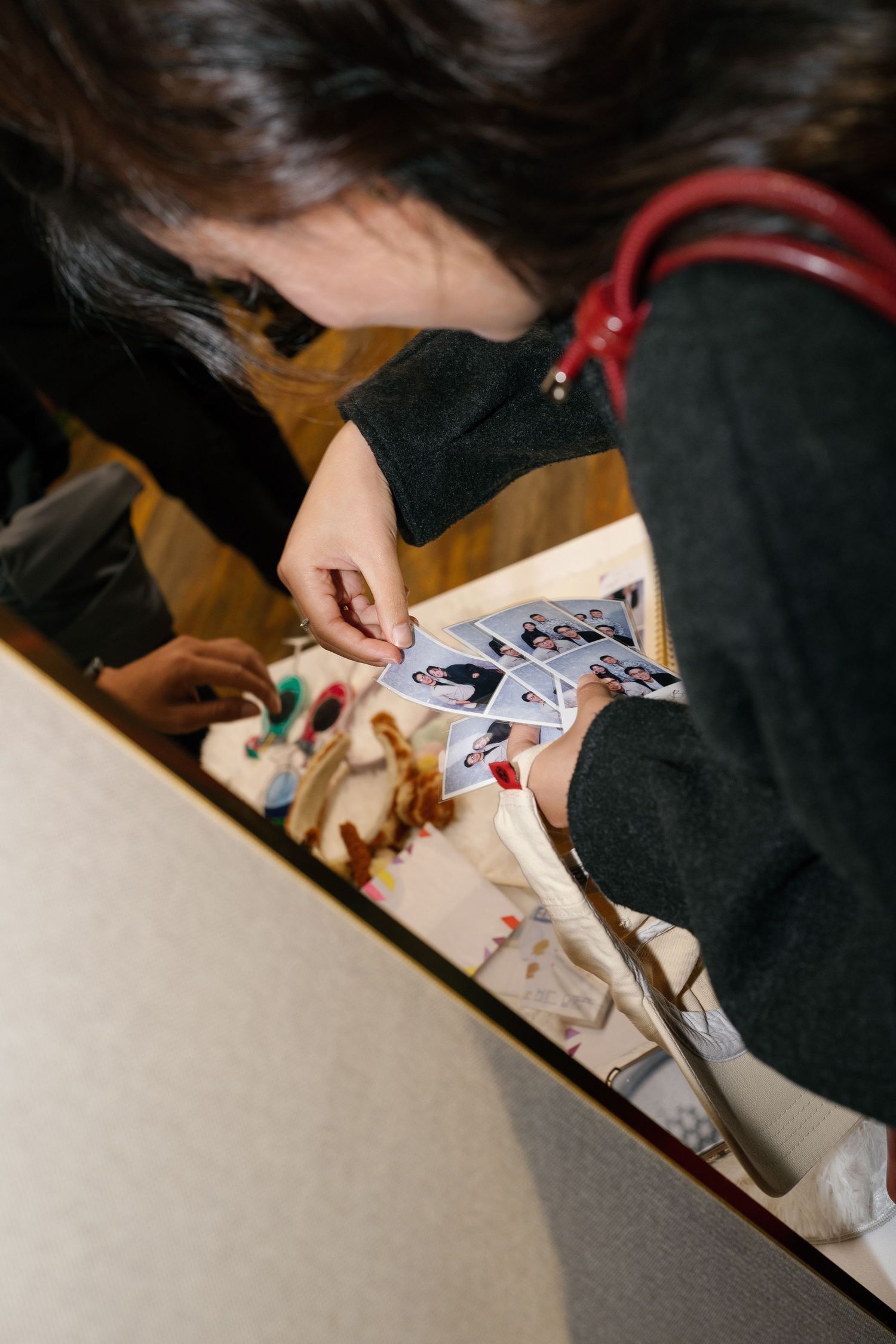 Guest browsing wedding photo booth prints at a decorated table during a reception event.