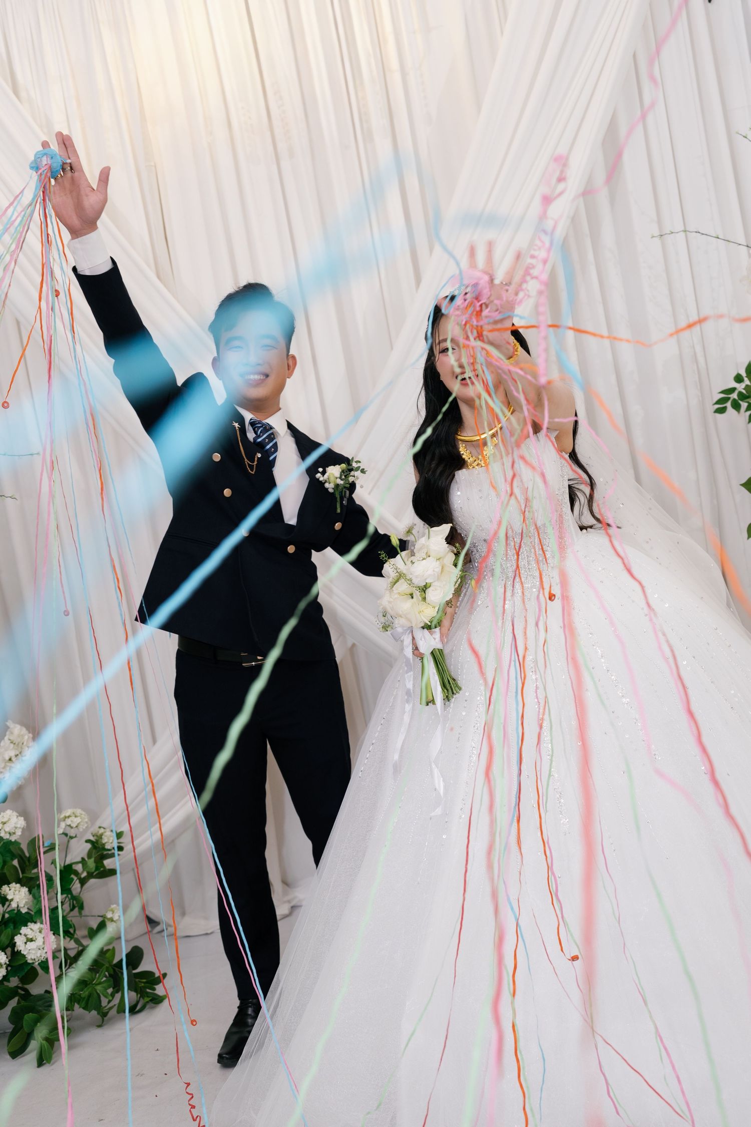 Bride and groom celebrate with colorful streamers at their wedding reception ceremony.