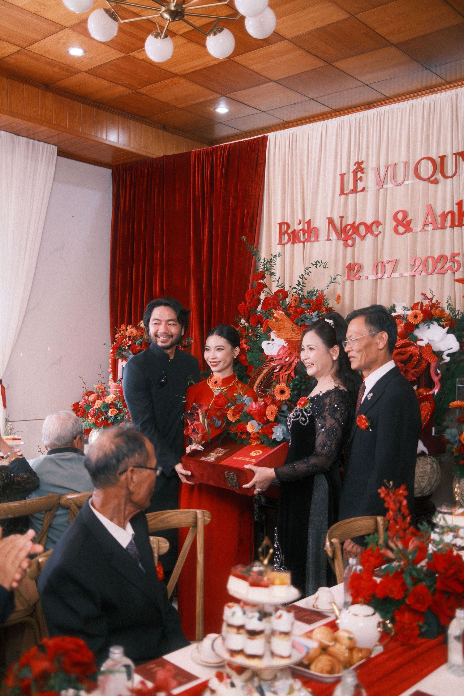 Vietnamese wedding ceremony with couple in traditional red ao dai exchanging gifts with family on 12.07.2025.