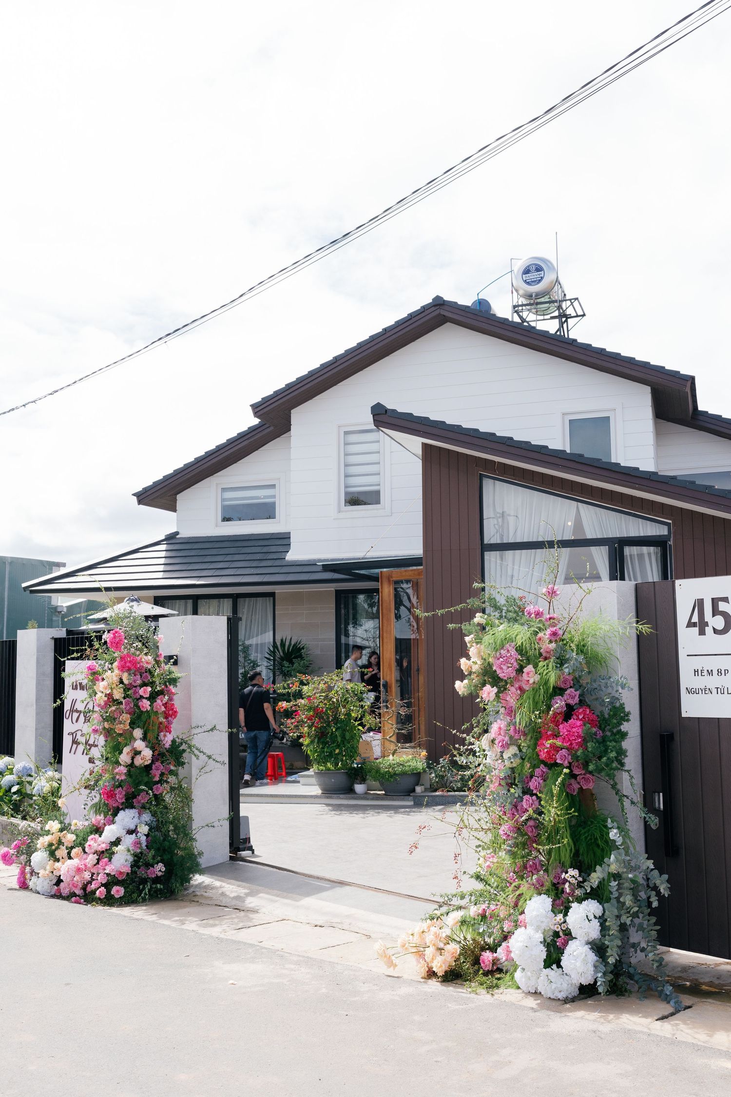 Japanese-style house entrance decorated with pink and white floral arch arrangements for wedding celebration.